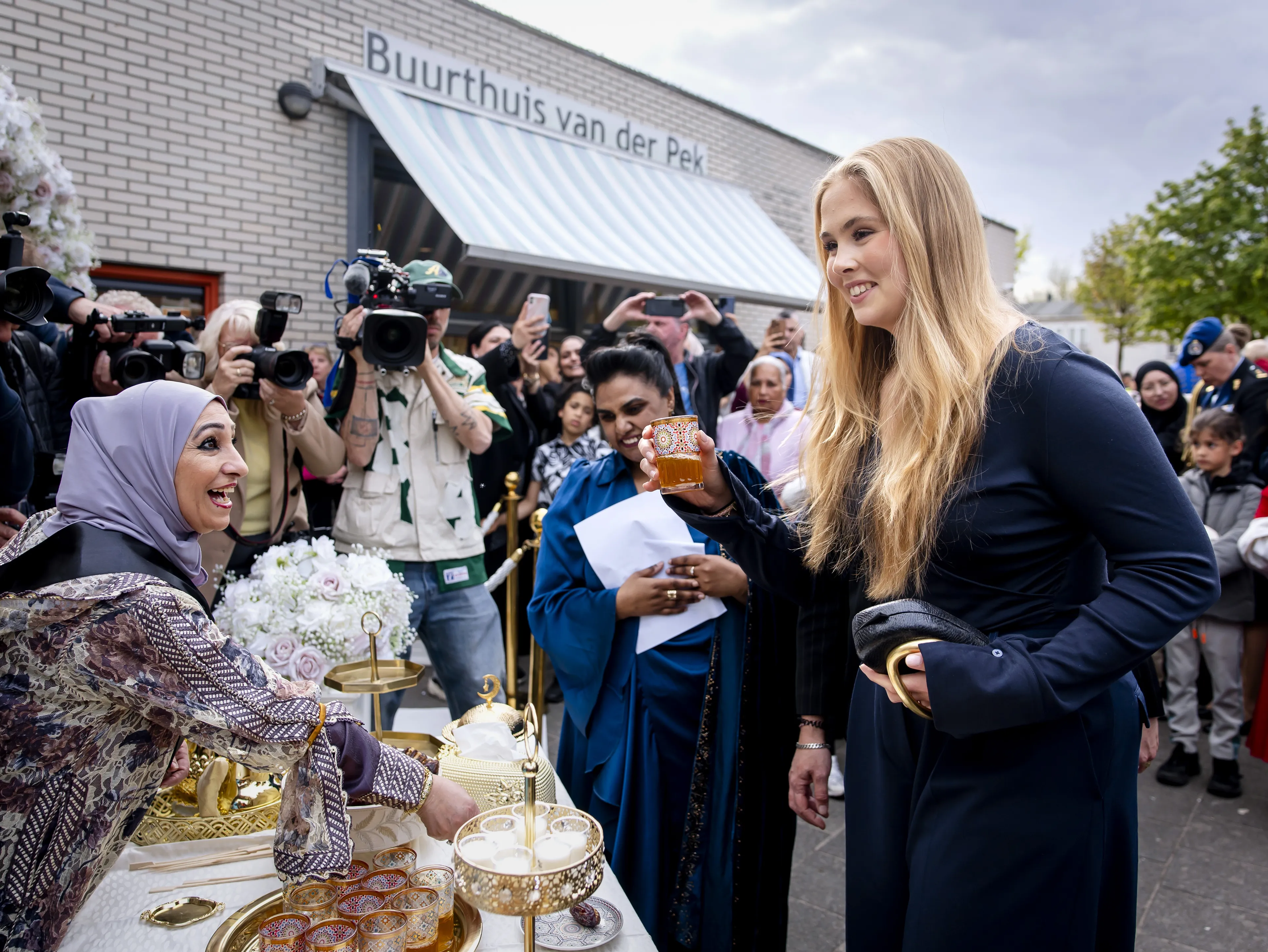 Voor het buurthuis krijgt de prinses wat te drinken aangeboden.
