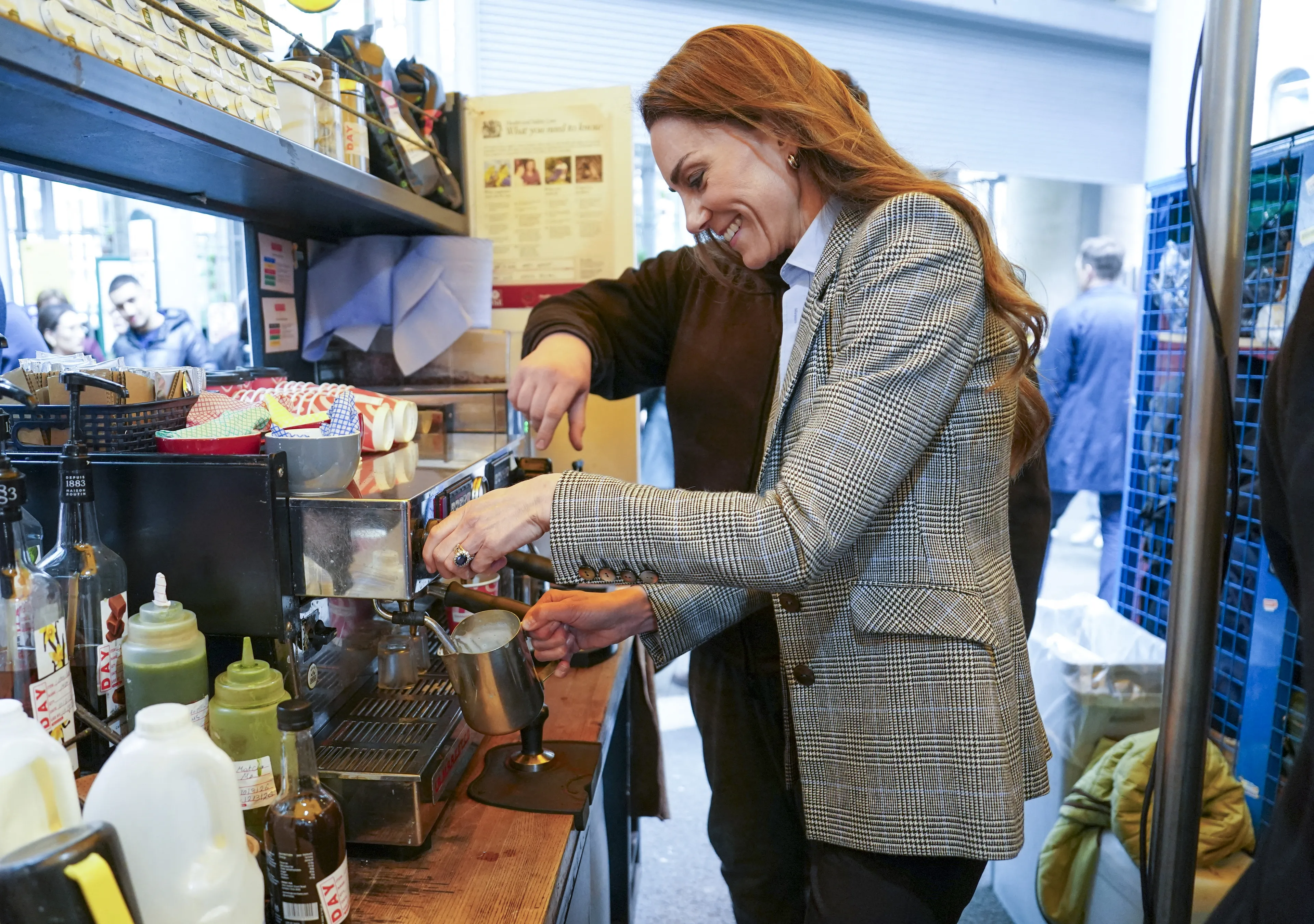 Catherine, de prinses van Wales leert hoe ze melk op moet schuimen.
