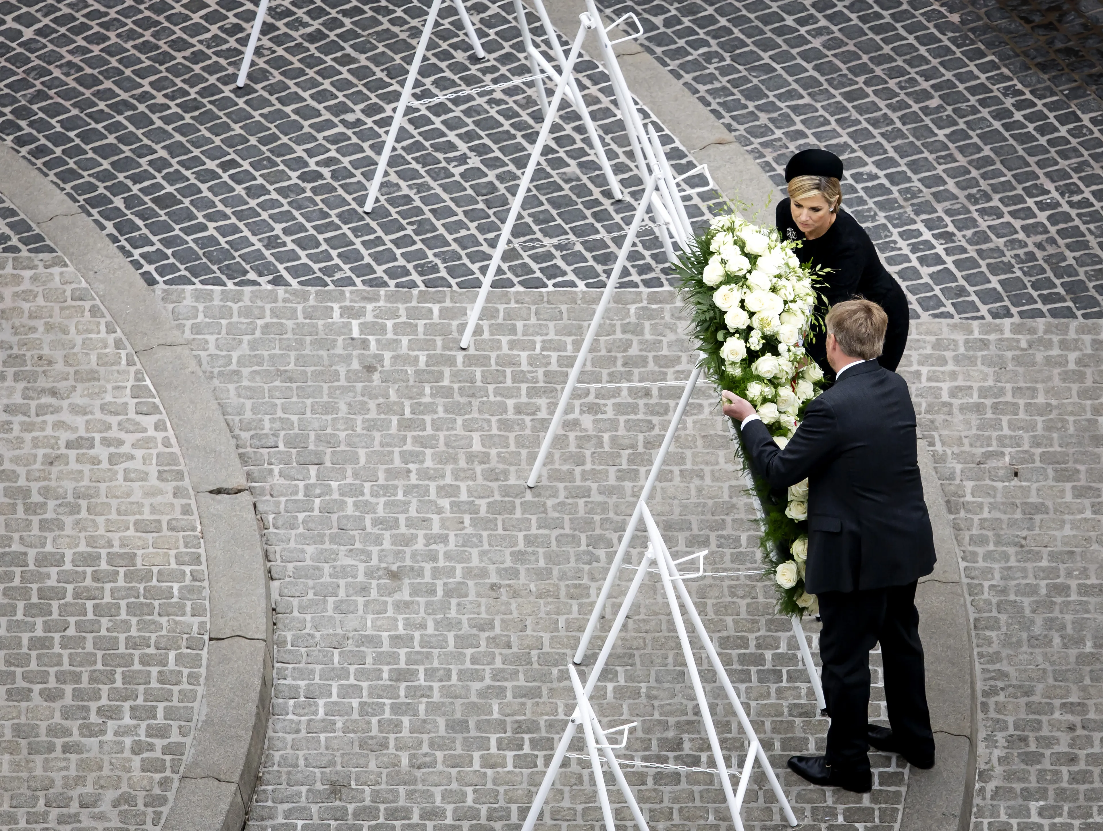 Het koningspaar legt als eerste een krans bij het monument.