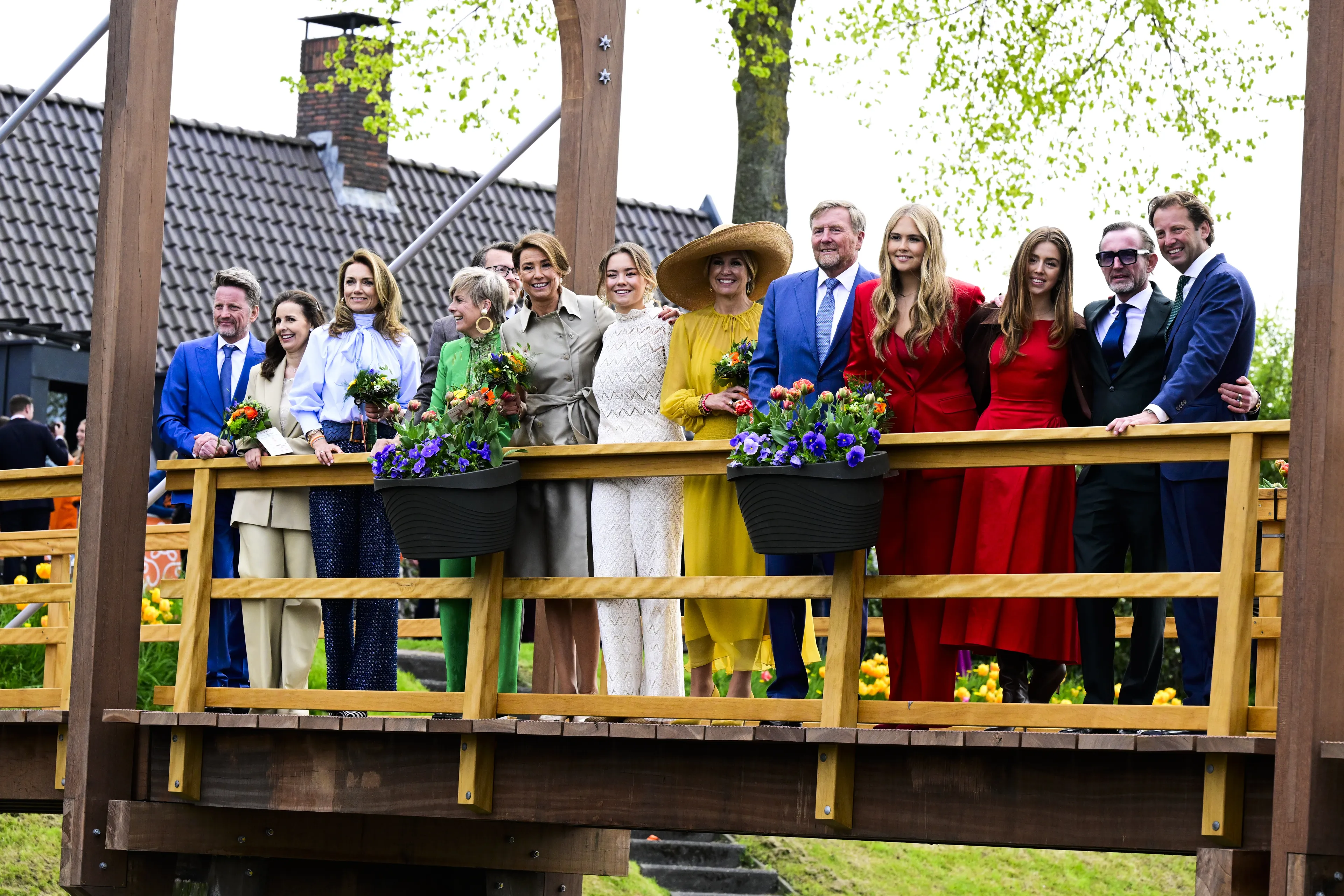 De koninklijke familie staat vanaf de brug naar het podium te kijken.