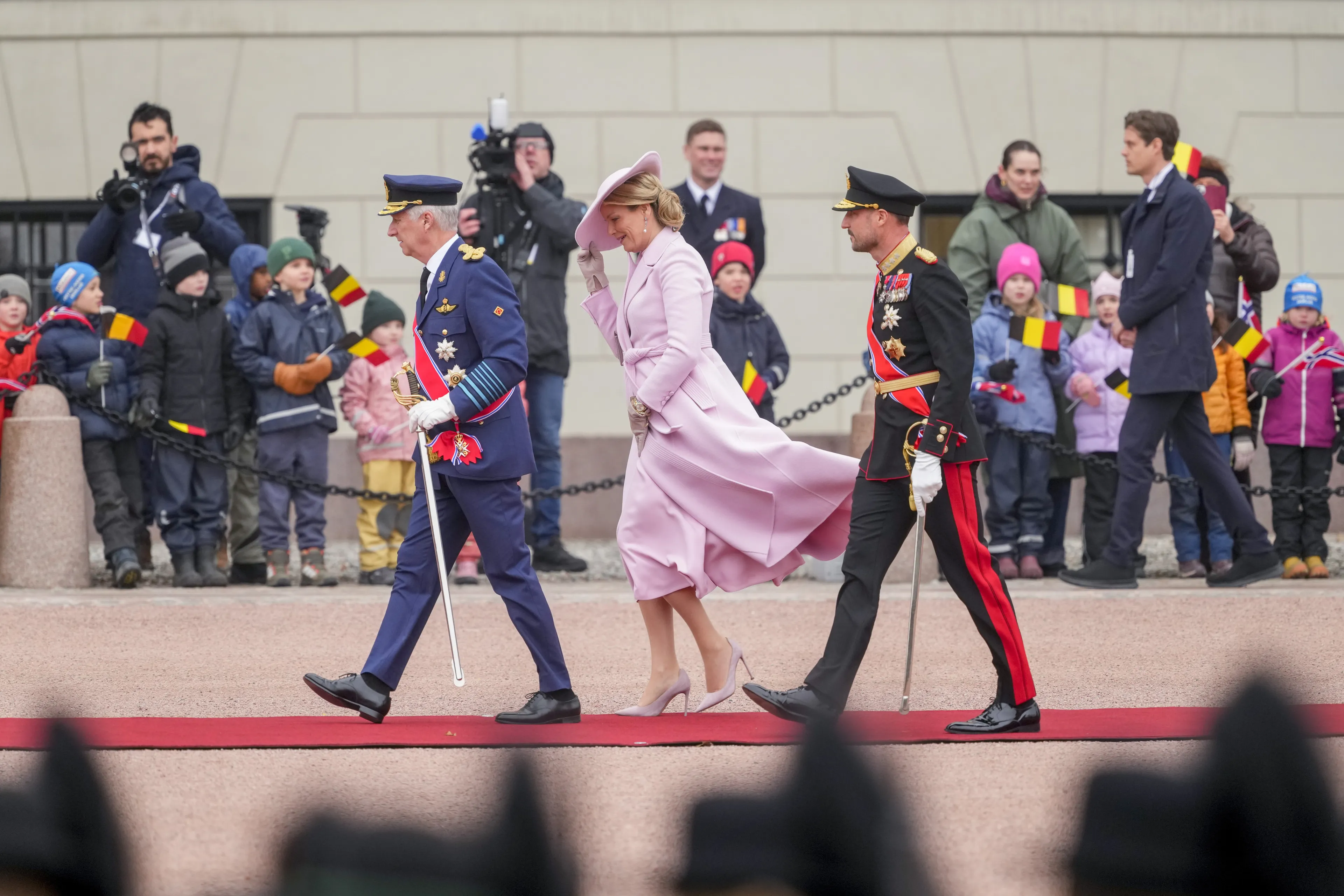 Koningin Mathilde moet haar hoed goed vasthouden vanwege de stevige wind in Oslo.