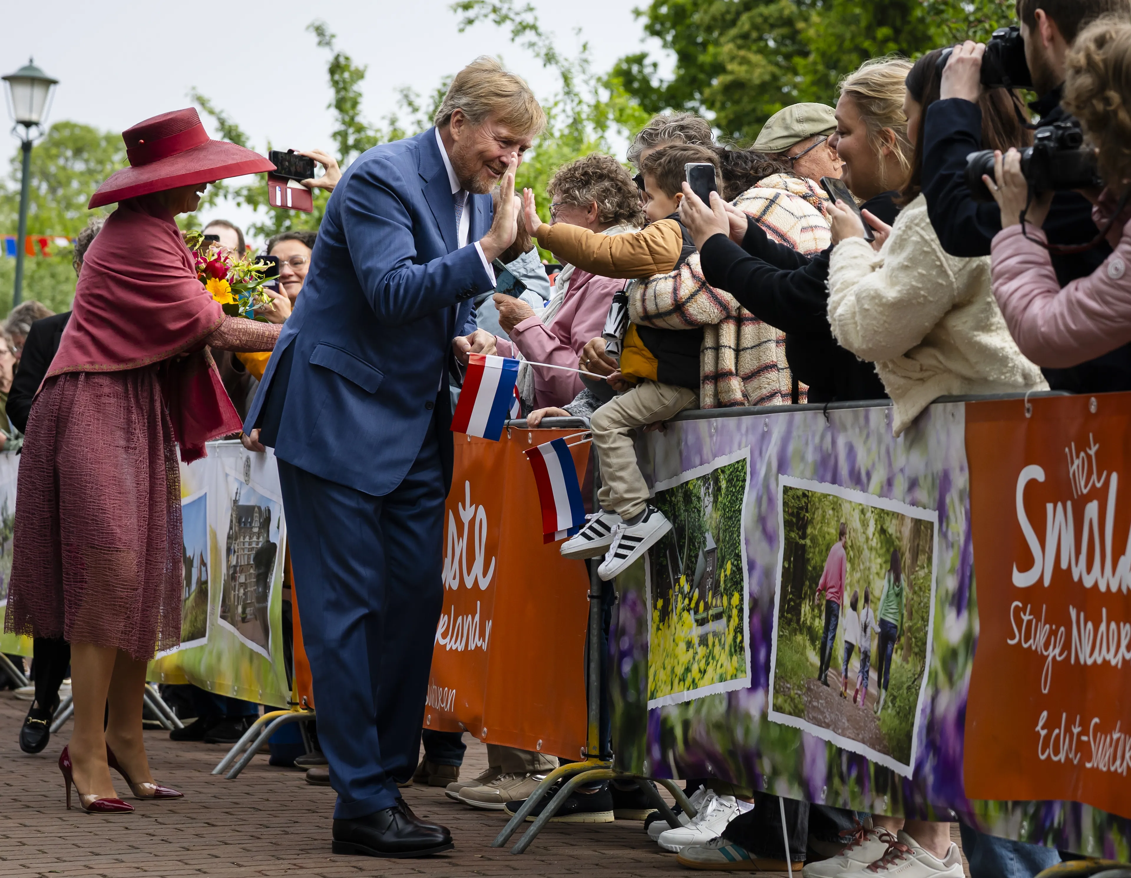 Een kleine toeschouwer krijgt een high five van de koning.