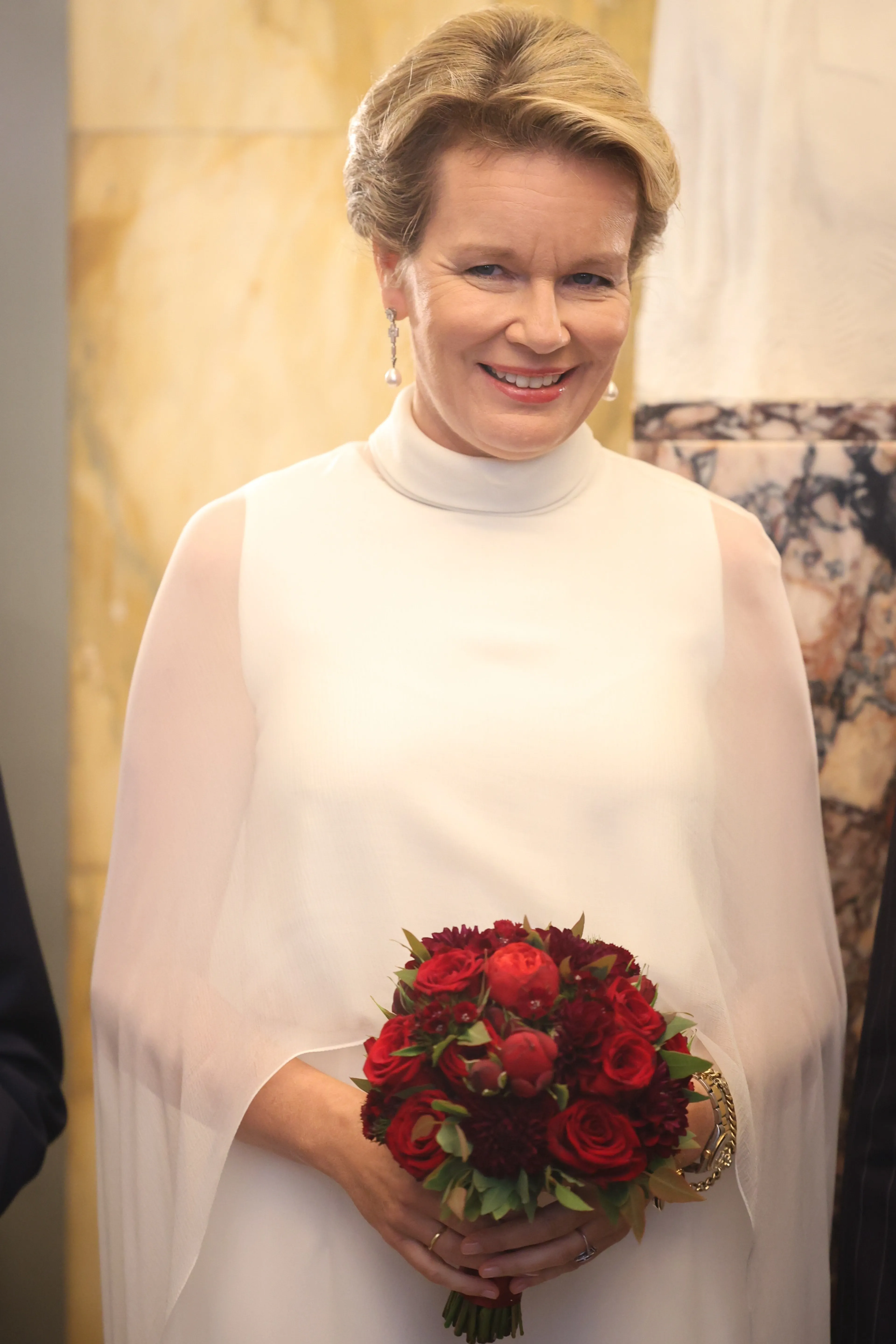 De doorzichtige cape valt over de armen heen.