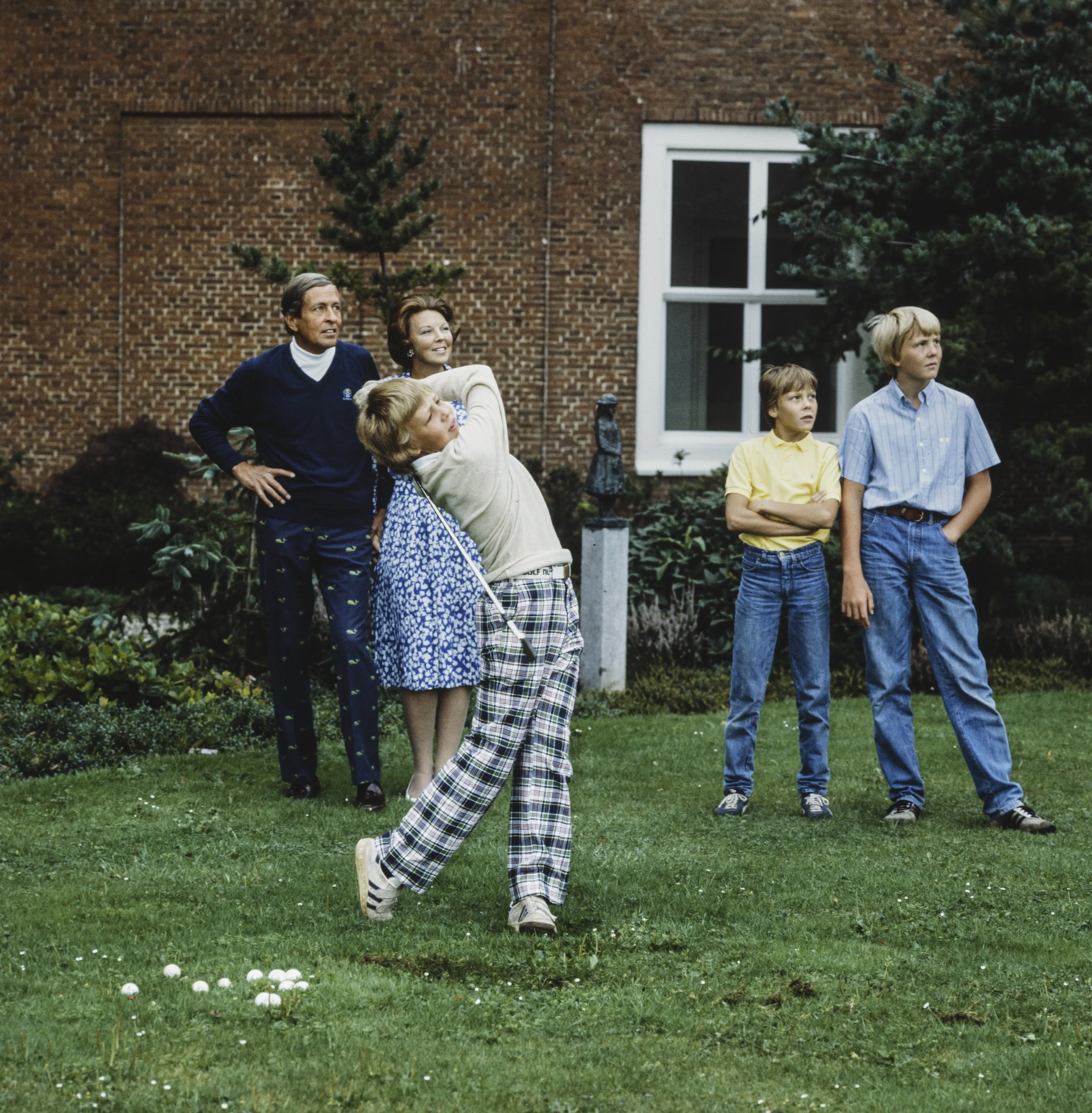 De gezinsleden kijken toe hoe prins Friso een balletje slaat (1982).