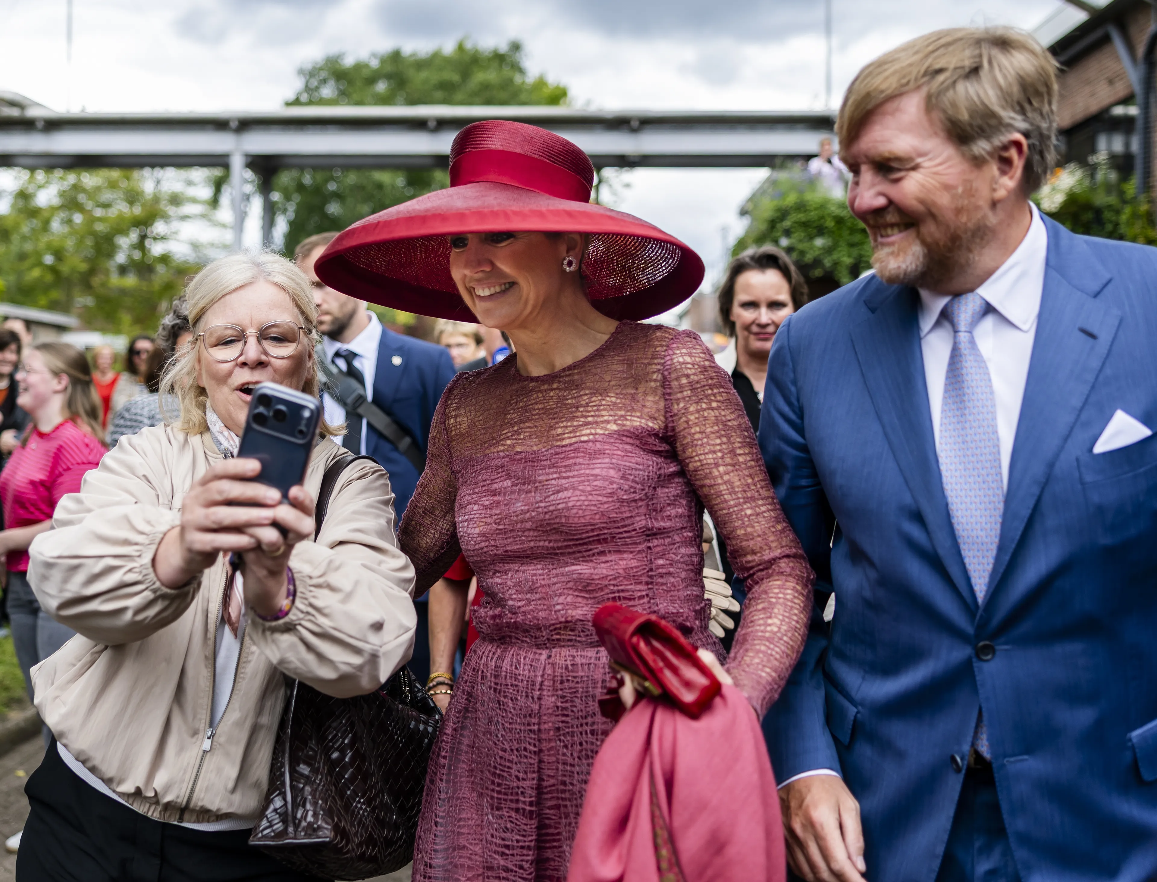 De koning en koningin nemen de tijd om op de foto te gaan met mensen langs de kant.