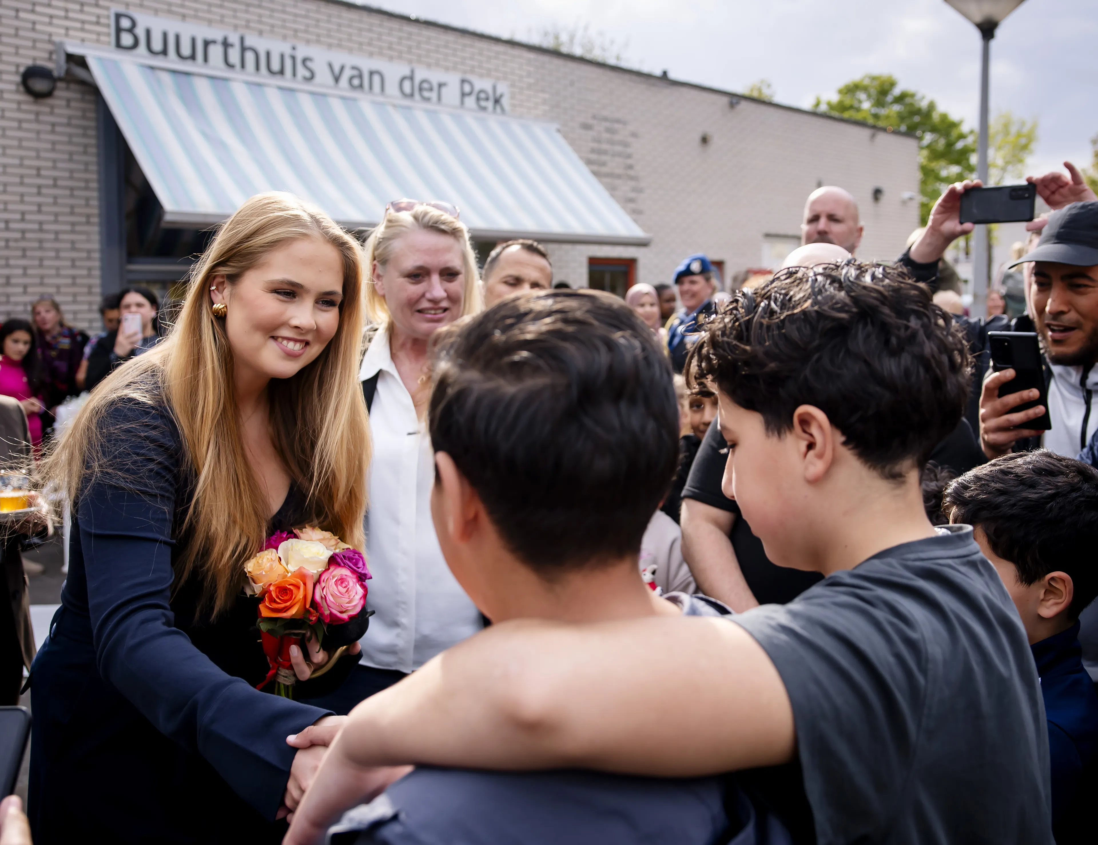 De prinses krijgt een bloemetje van twee jongens.