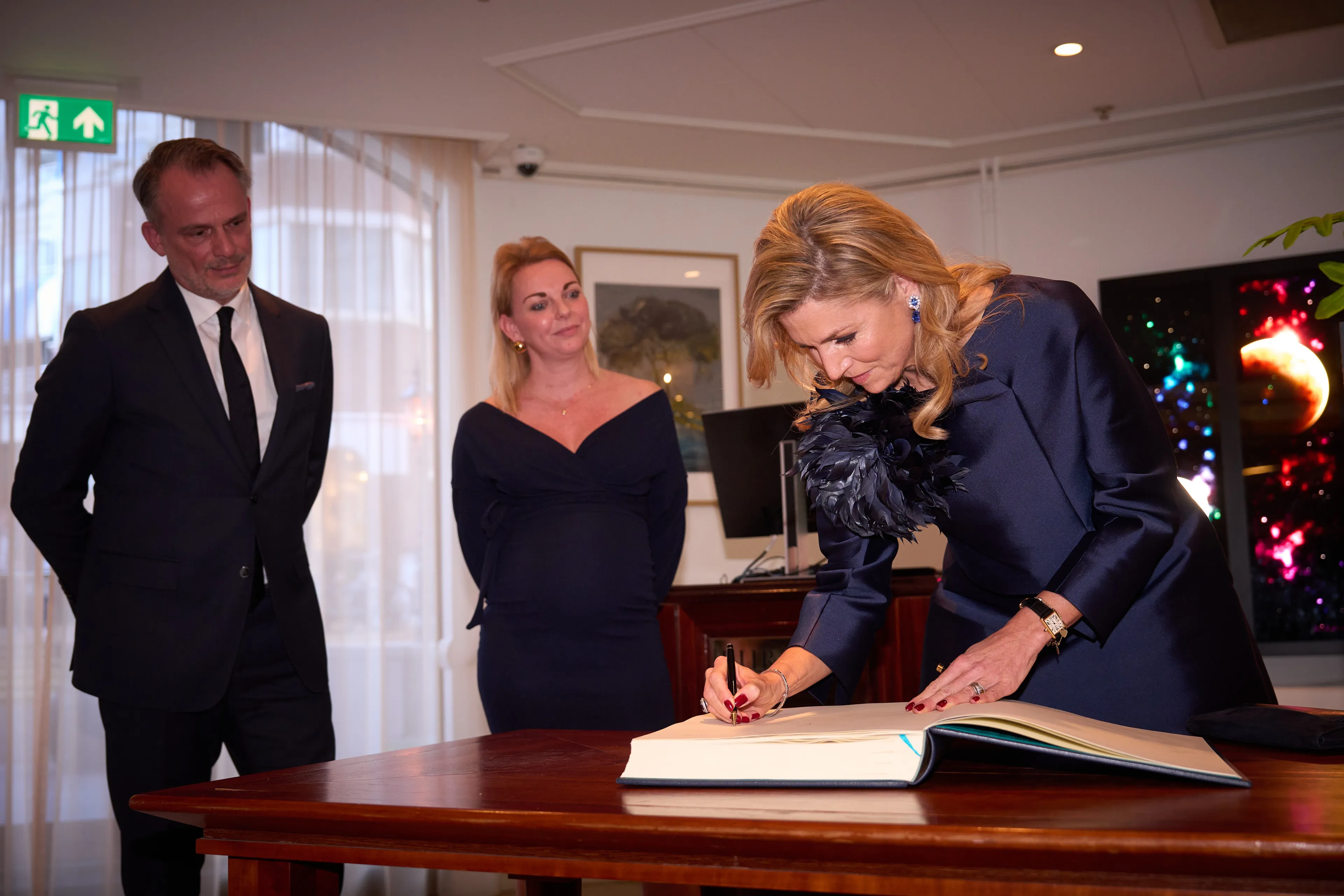 Koningin Máxima tekent in het gastenboek van het hotel.