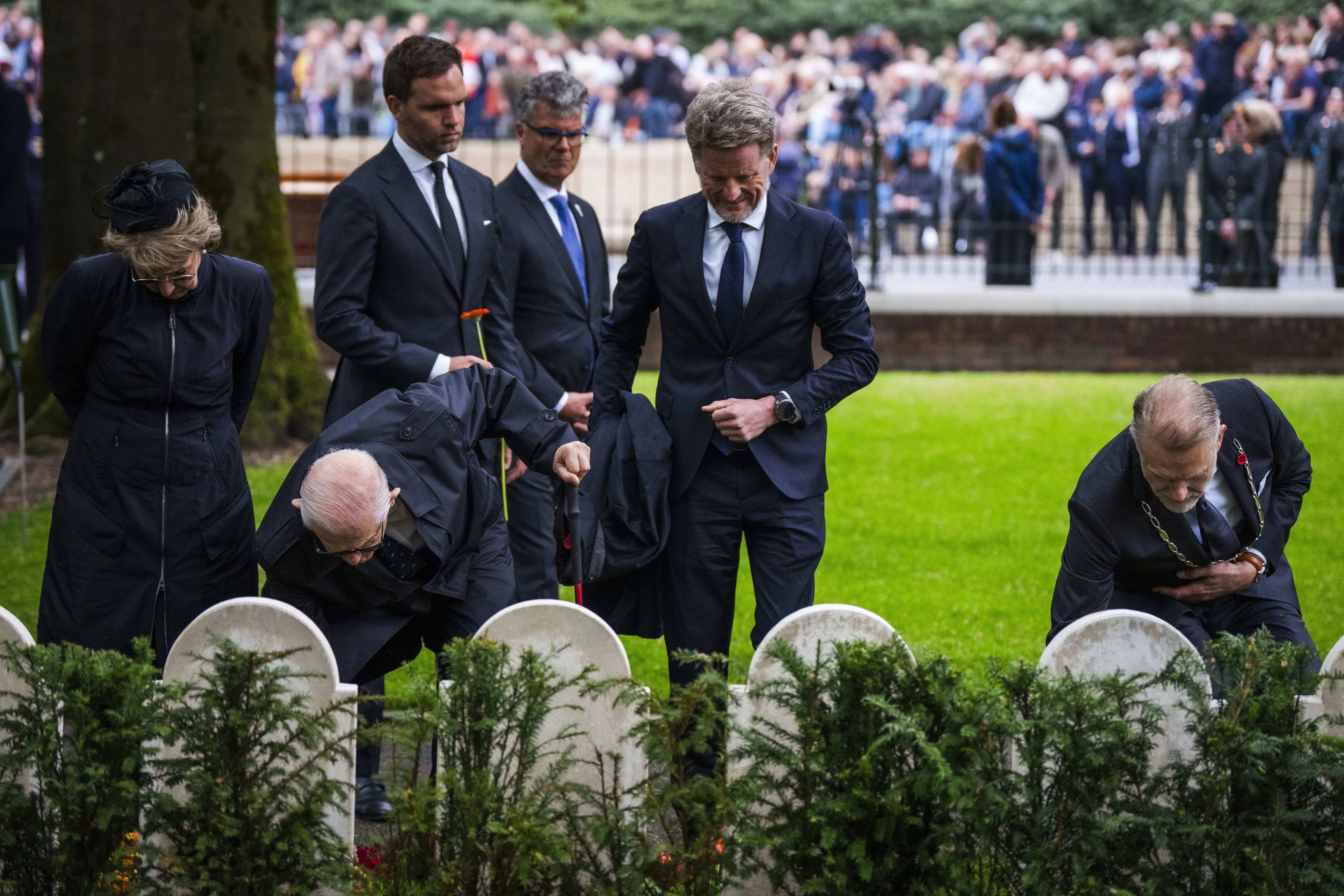 Pieter van Vollenhoven legt een bloem bij een graf.