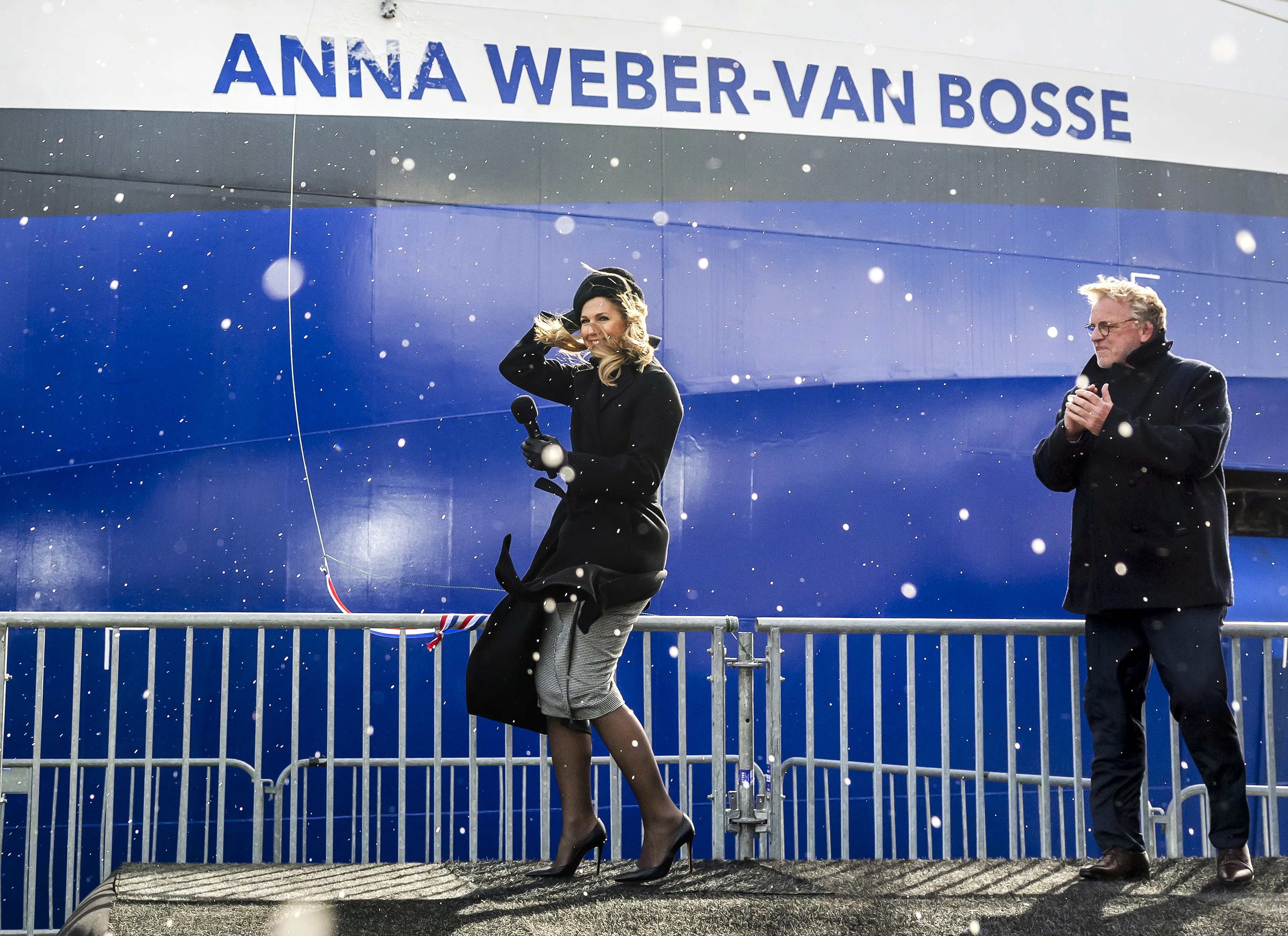 De koningin krijgt overal spetters van champagne over zich heen.