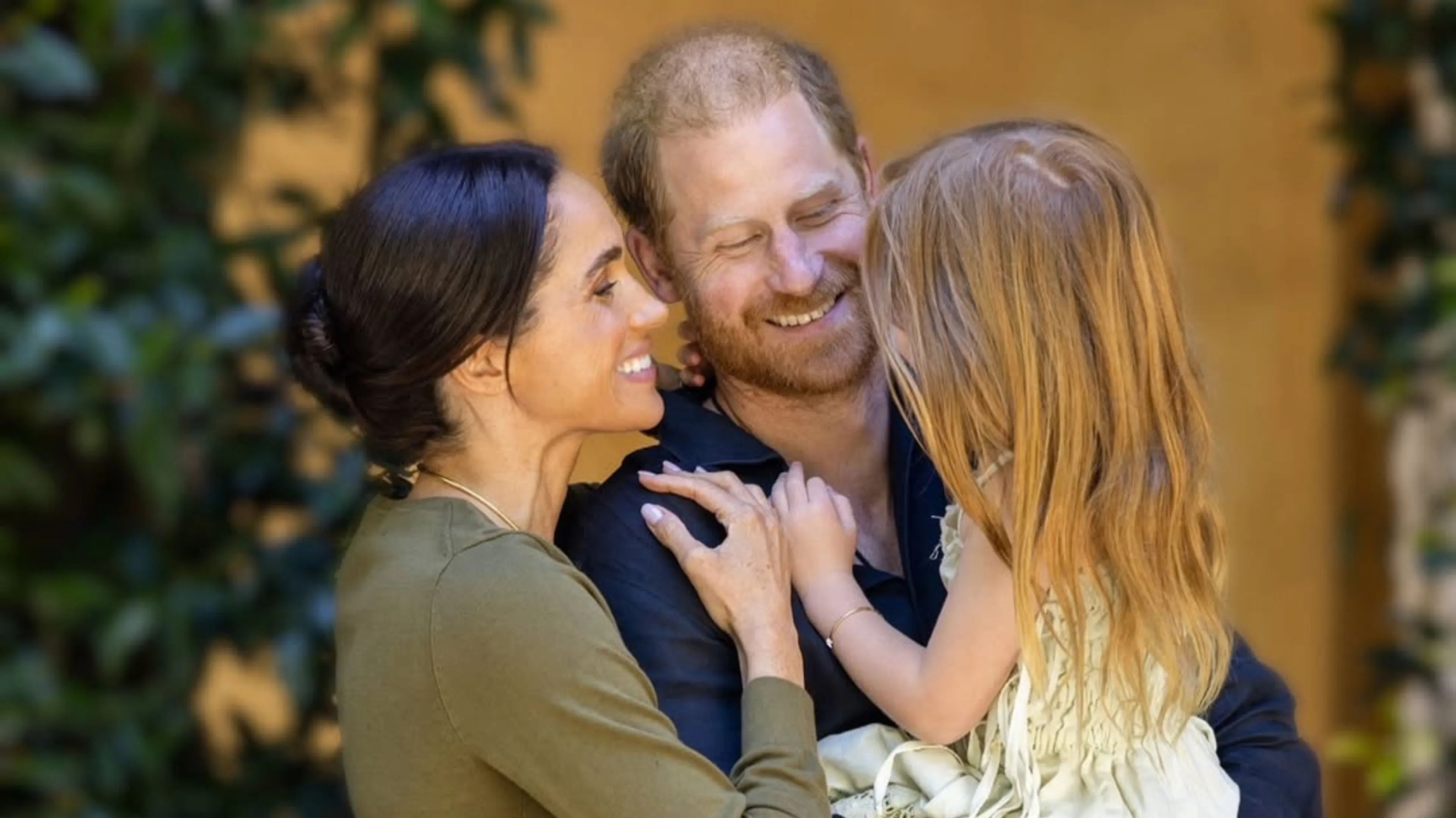 Gezinsknuffel: een volwassen vrouw, een volwassen man en een jong meisje komen dicht tegen elkaar aan in een warme, intieme moment, terwijl het trio lacht en elkaar vasthoudt in een tedere omhelzing.