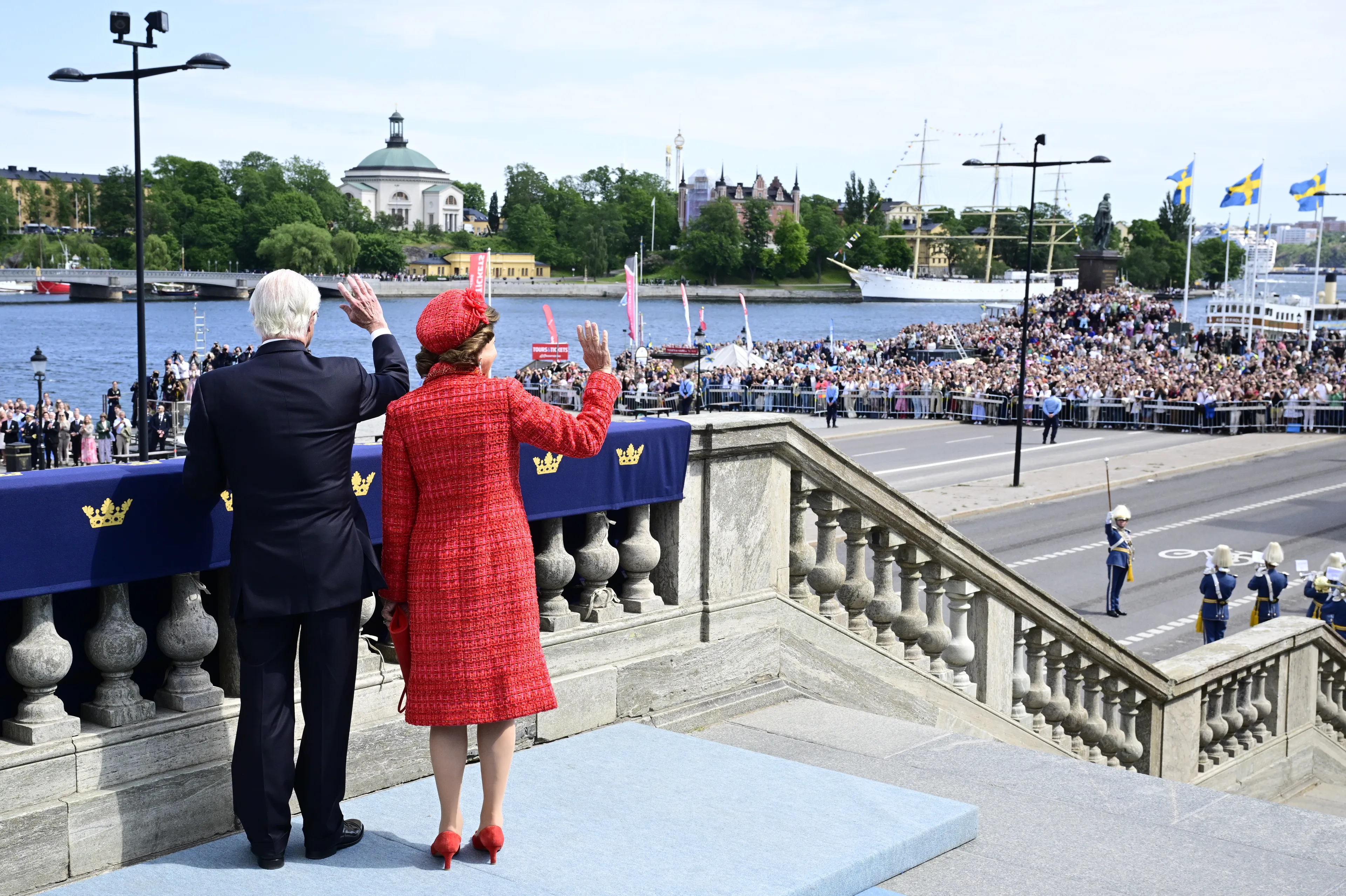 Koning Carl Gustaf en koningin Silvia zwaaien naar het publiek.
