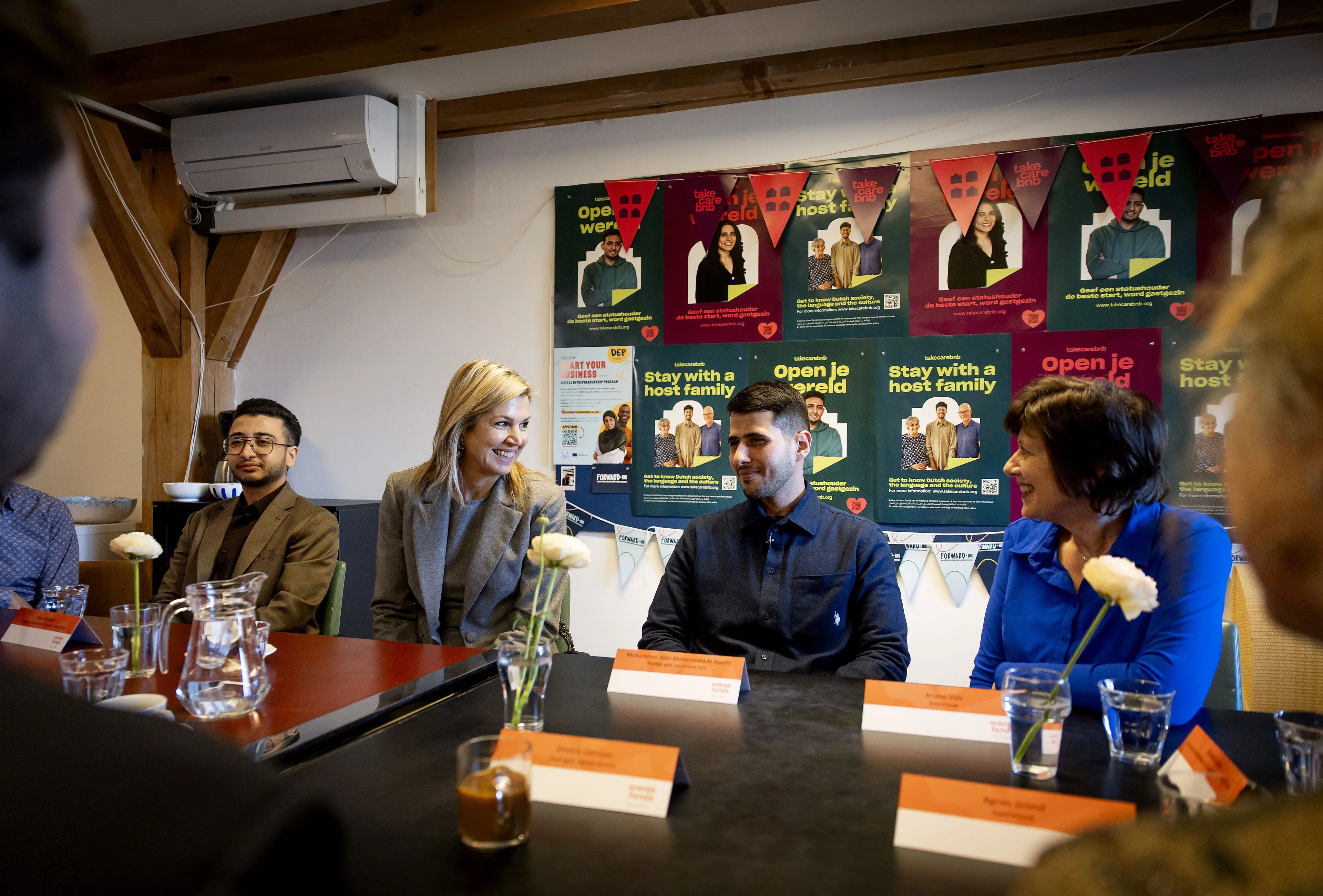 De koningin spreekt met vluchtelingen en gastgezinnen.