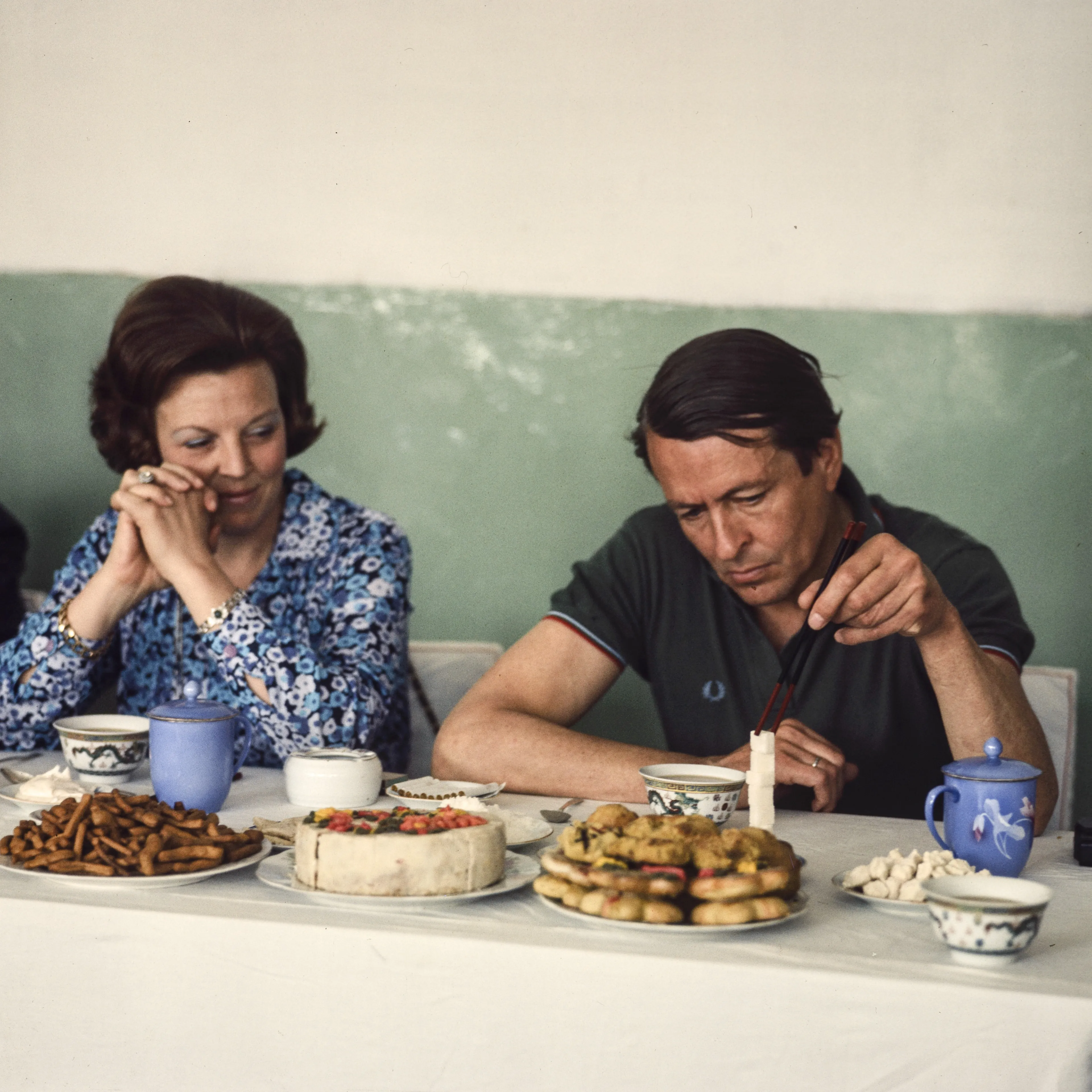 Prins Claus en koningin Beatrix met taart en koekjes voor zich.