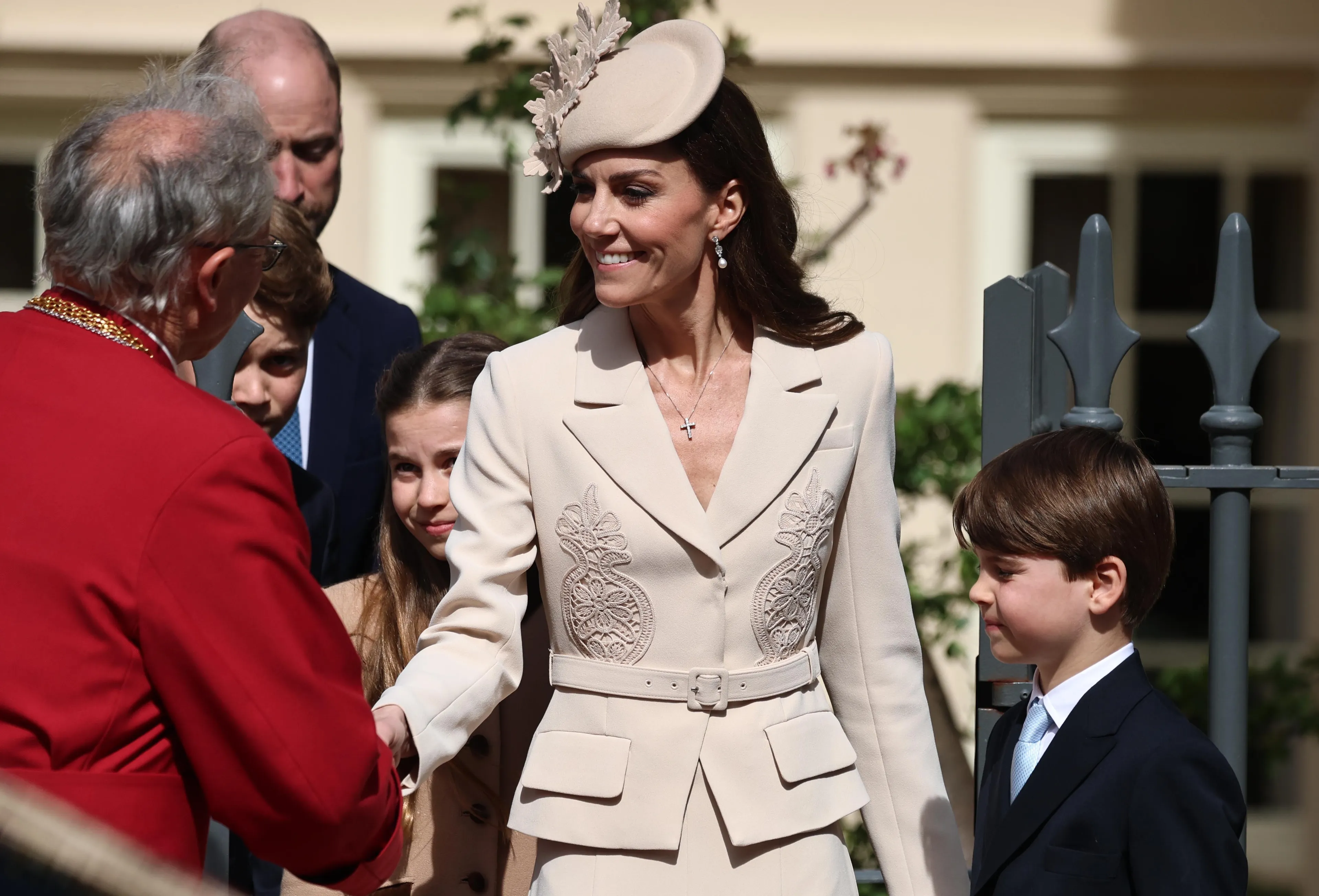 Catherine draagt een beige japon.