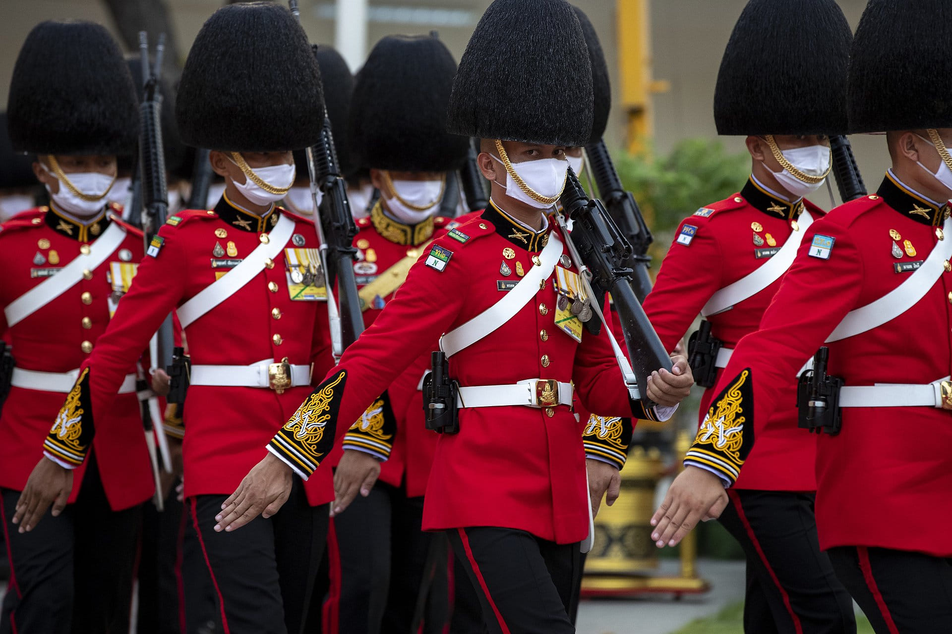 Een eregarde met mondkapjes bereidt zich voor op de komst van koning Maha Vajiralongkorn en koningin