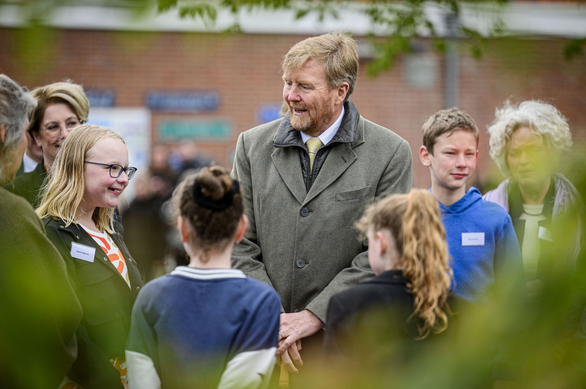 Op het schoolplein spreekt de koning met kinderen die hebben meegedacht over de vergroening van hun schoolplein.