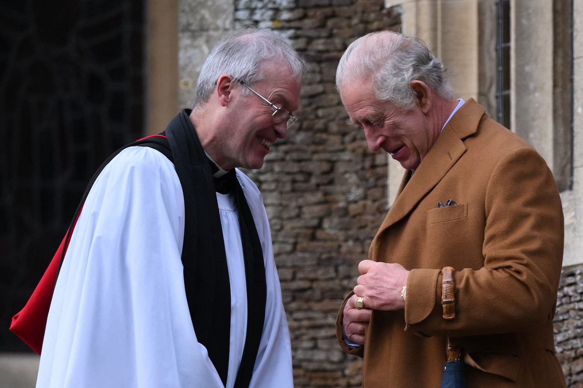 Koning Charles praat met de priester van de kerk in Sandringham na de dienst in 2022.