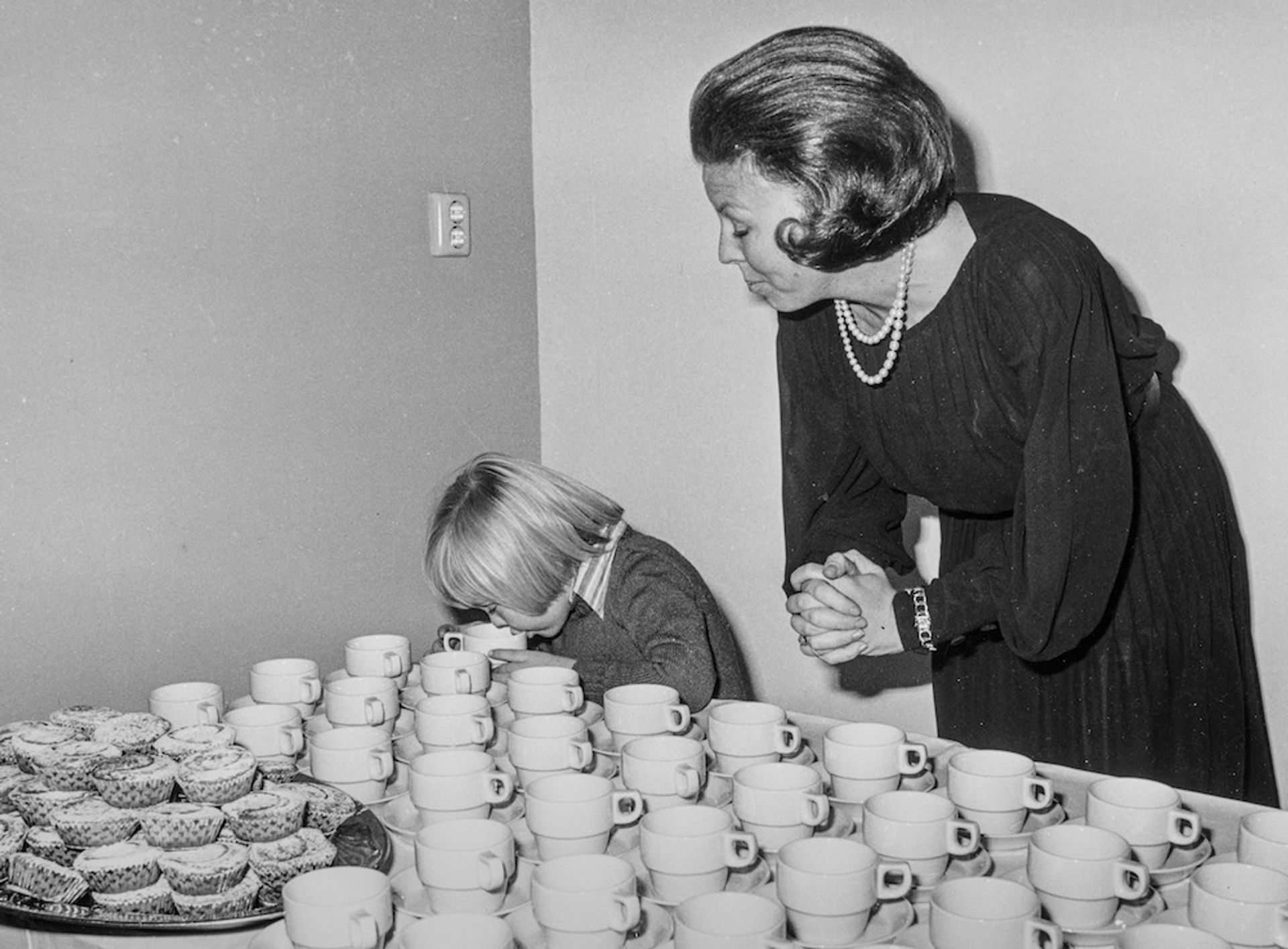 Prinses Beatrix en prins Willem-Alexander delen chocolademelk en broodjes uit aan het personeel.