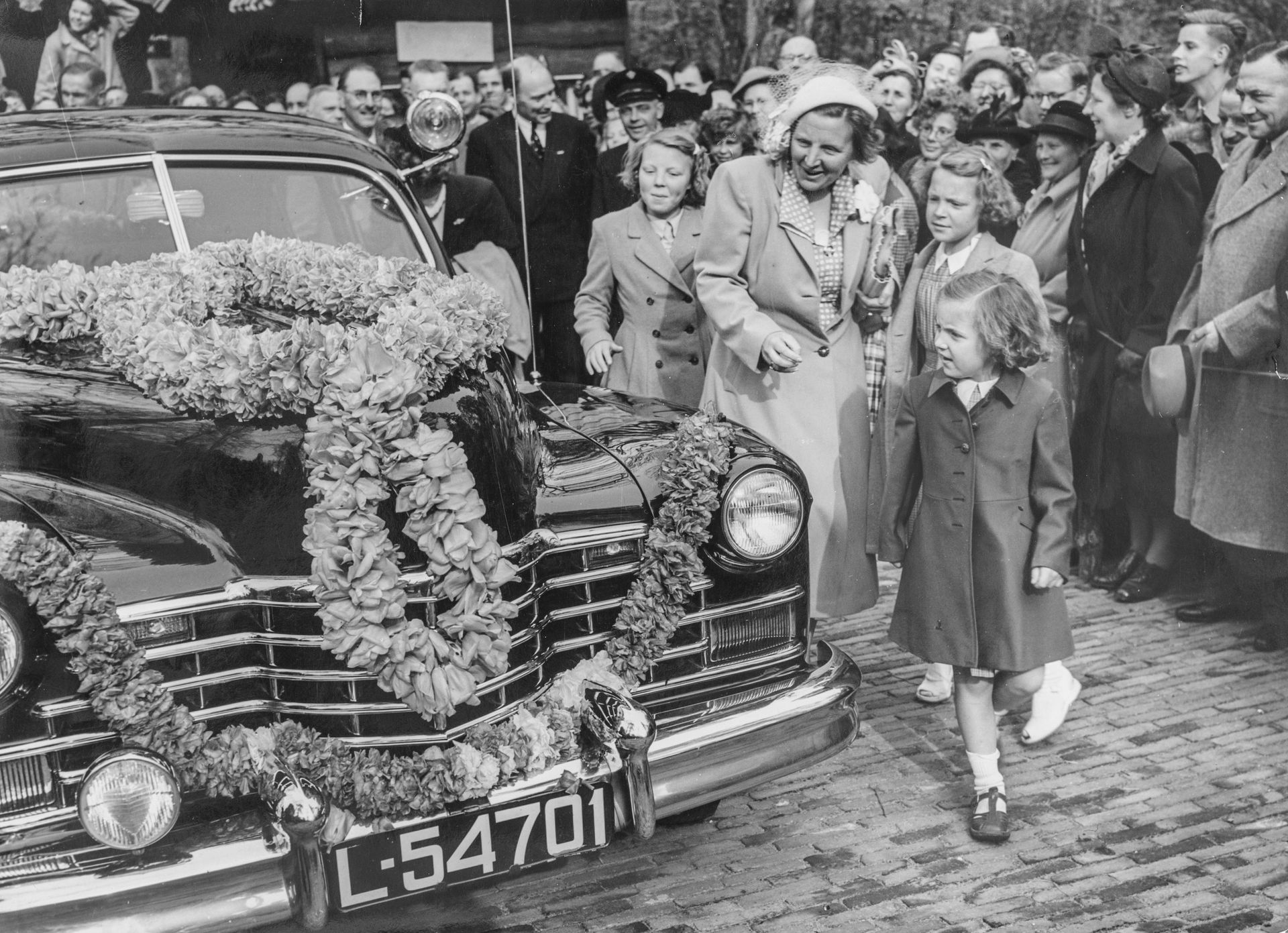 Koningin Juliana met haar drie oudste dochters bij met bloemen versierde Cadillac