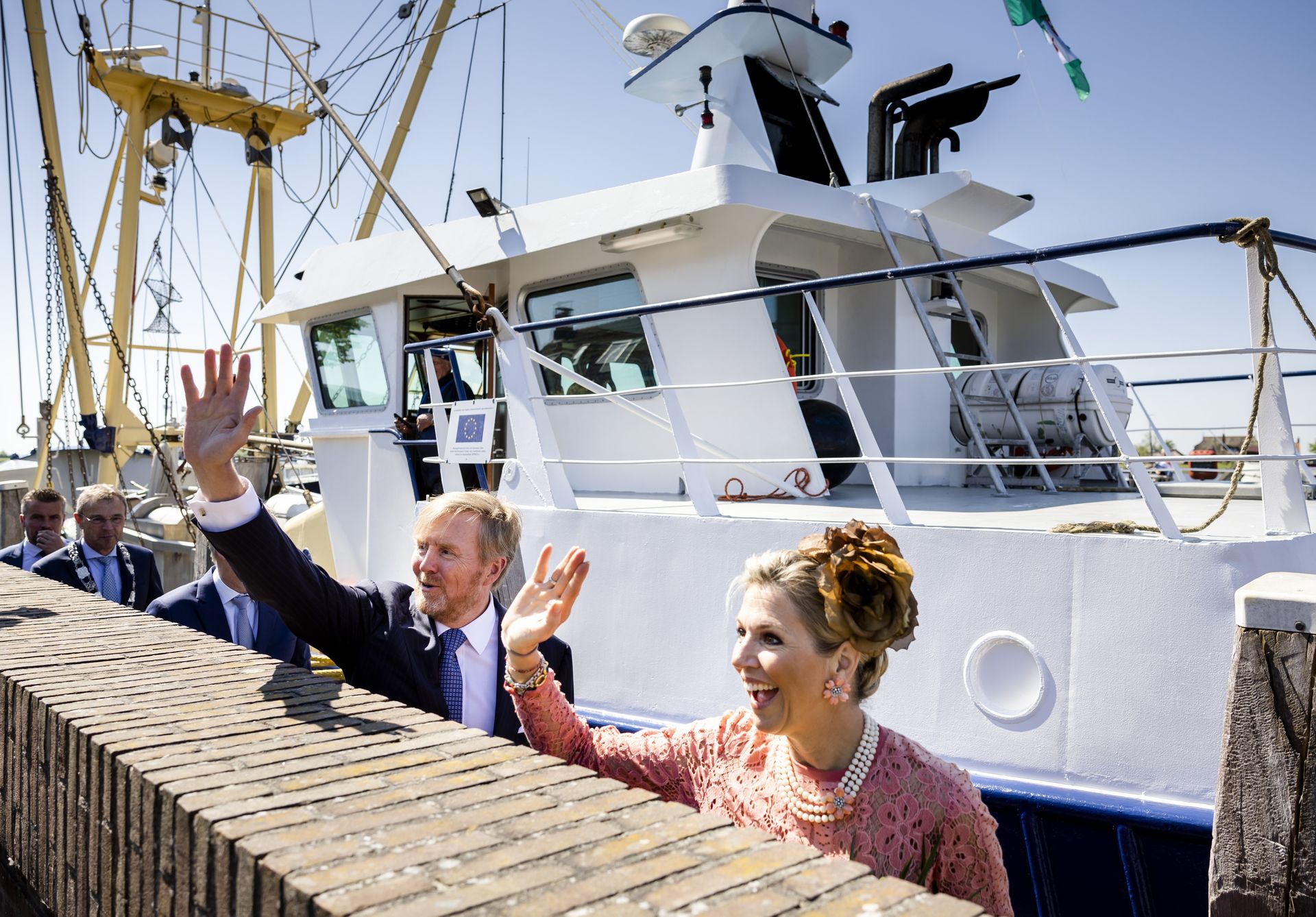 Koning Willem-Alexander en koningin Maxima bekijken een vissersschip tijdens een bezoek aan Zoutkamp.
