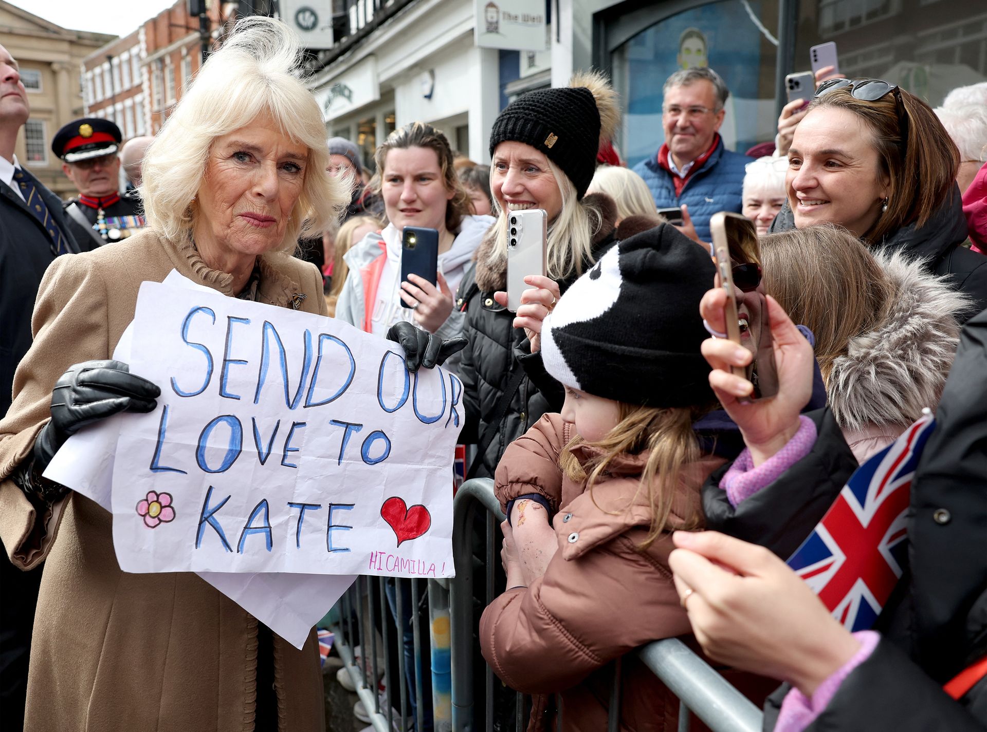 Koningin Camilla houdt tijdens haar bezoek aan de Farmers' Market op woensdag een spandoek vast met de tekst "Send our love to Kate"