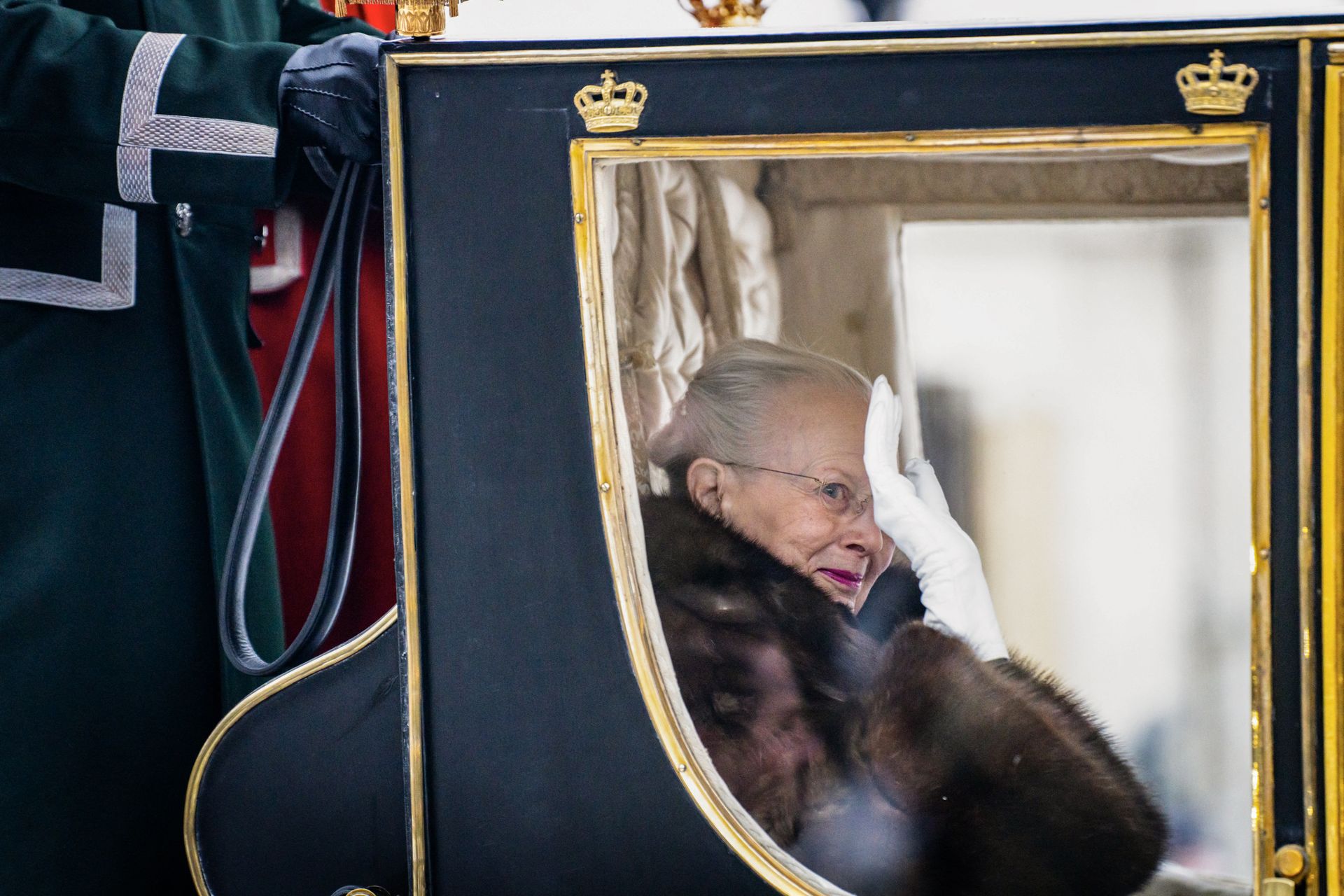 Koningin Margrethe zwaait naar het publiek in de gouden bruiloftskoets.