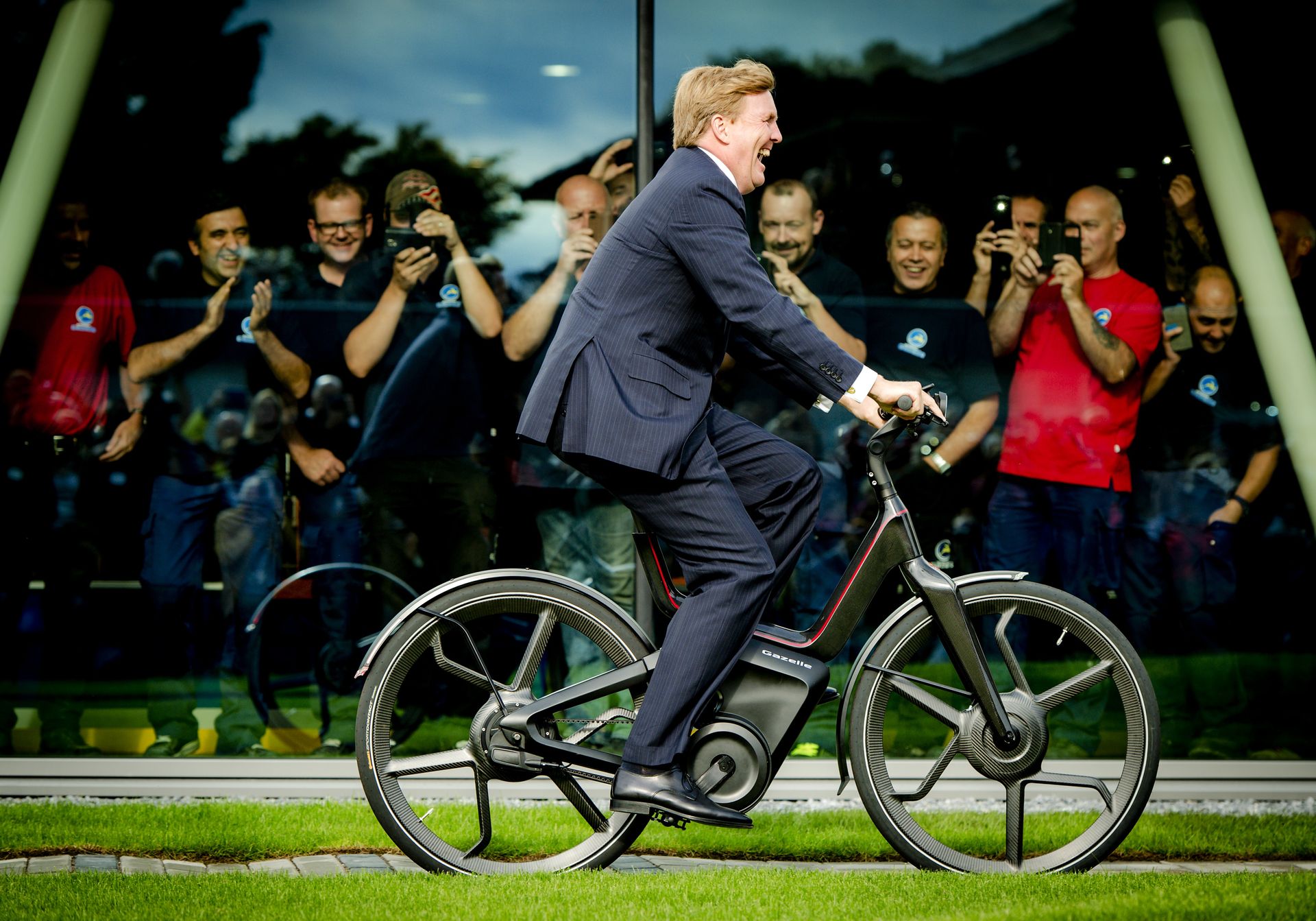 Koning Willem-Alexander fietst tijdens de opening van de nieuwe fietsfabriek.
