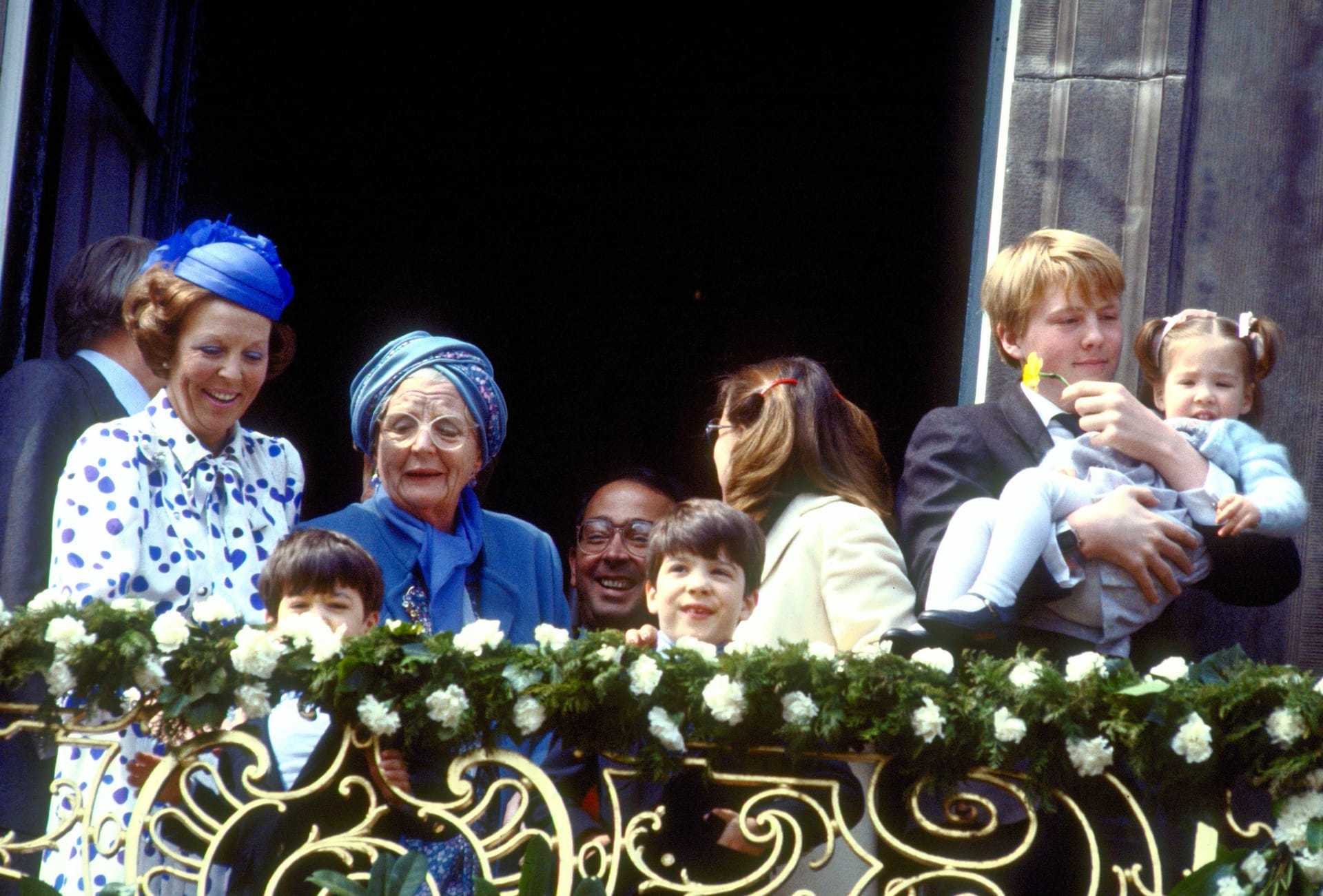 Prinses Juliana verschijnt op het balkon van paleis Lange Voorhout ter gelegenheid van haar 75e verjaardag. De 6-jarige Bernardo staat naast zijn jarige oma.