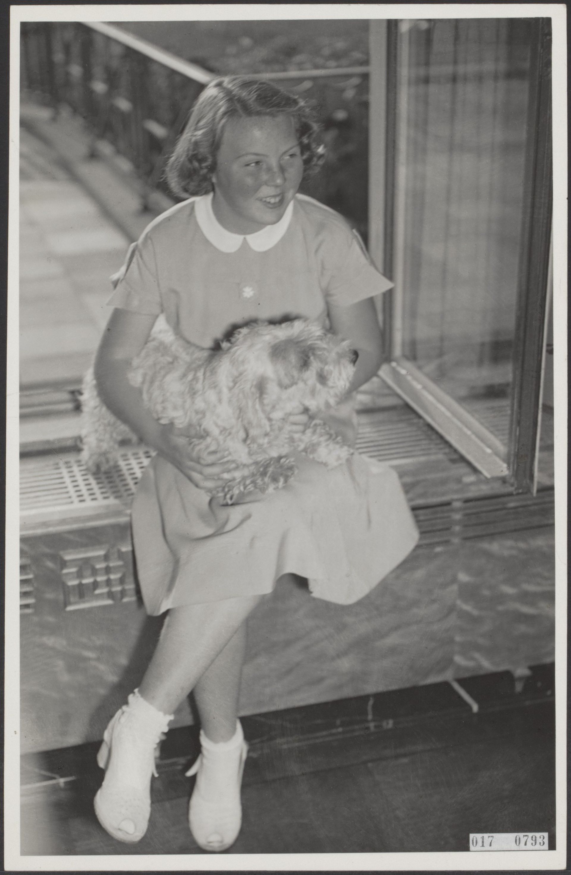Beatrix zit met haar hondje in een vensterbank van Paleis Soestdijk, 1951.
