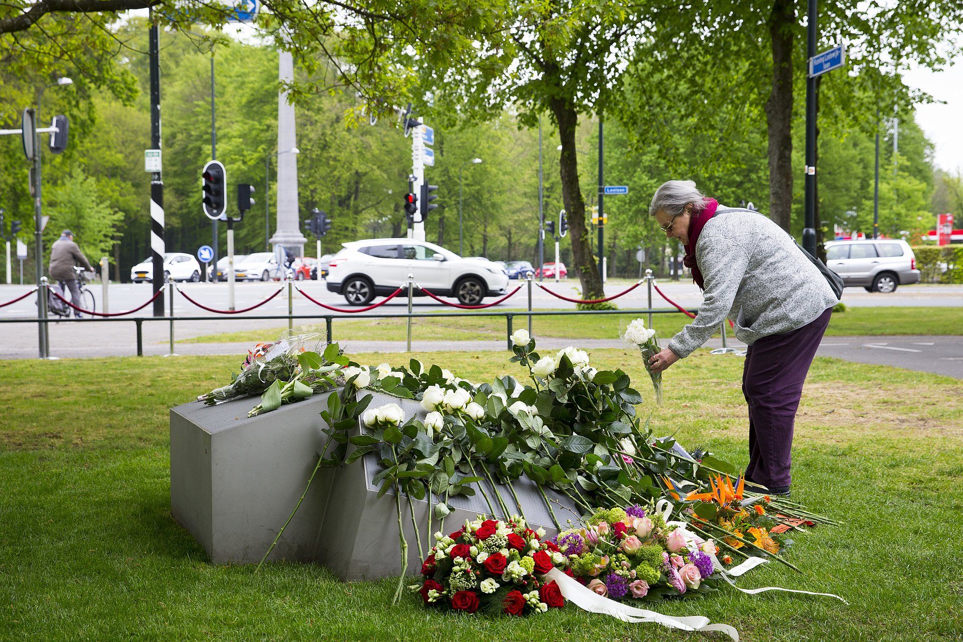 Een vrouw legt bloemen bij het herdenkingsmonument van de aanslag op Koninginnedag.