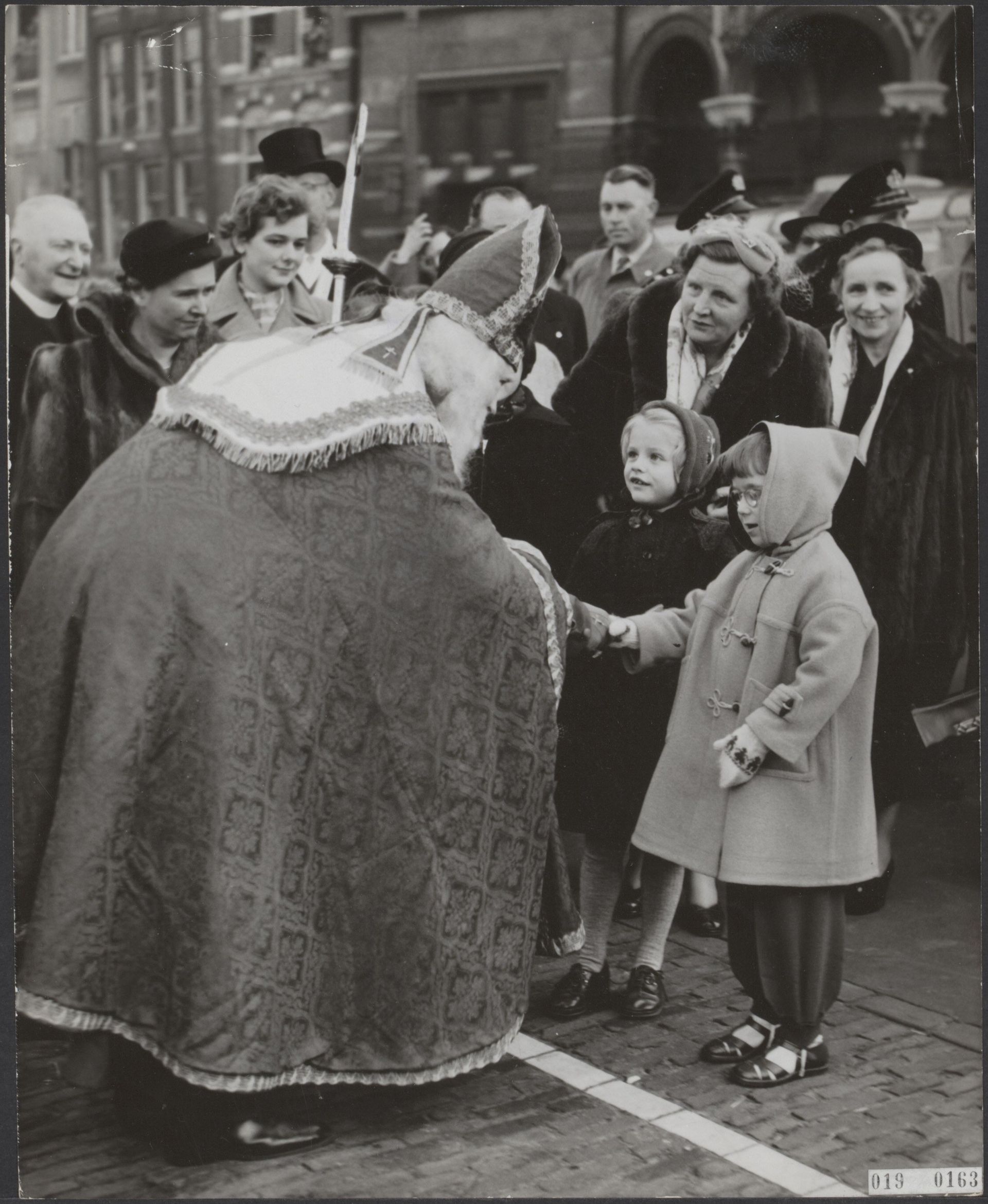 Kleine prinses Christina krijgt een hand van Sinterklaas, moeder Juliana kijkt toe. - 22 november 1954.