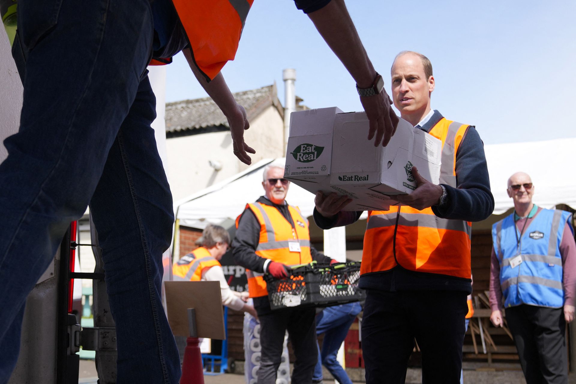 Prins William helpt bij het laden voedselpakketten in busjes.