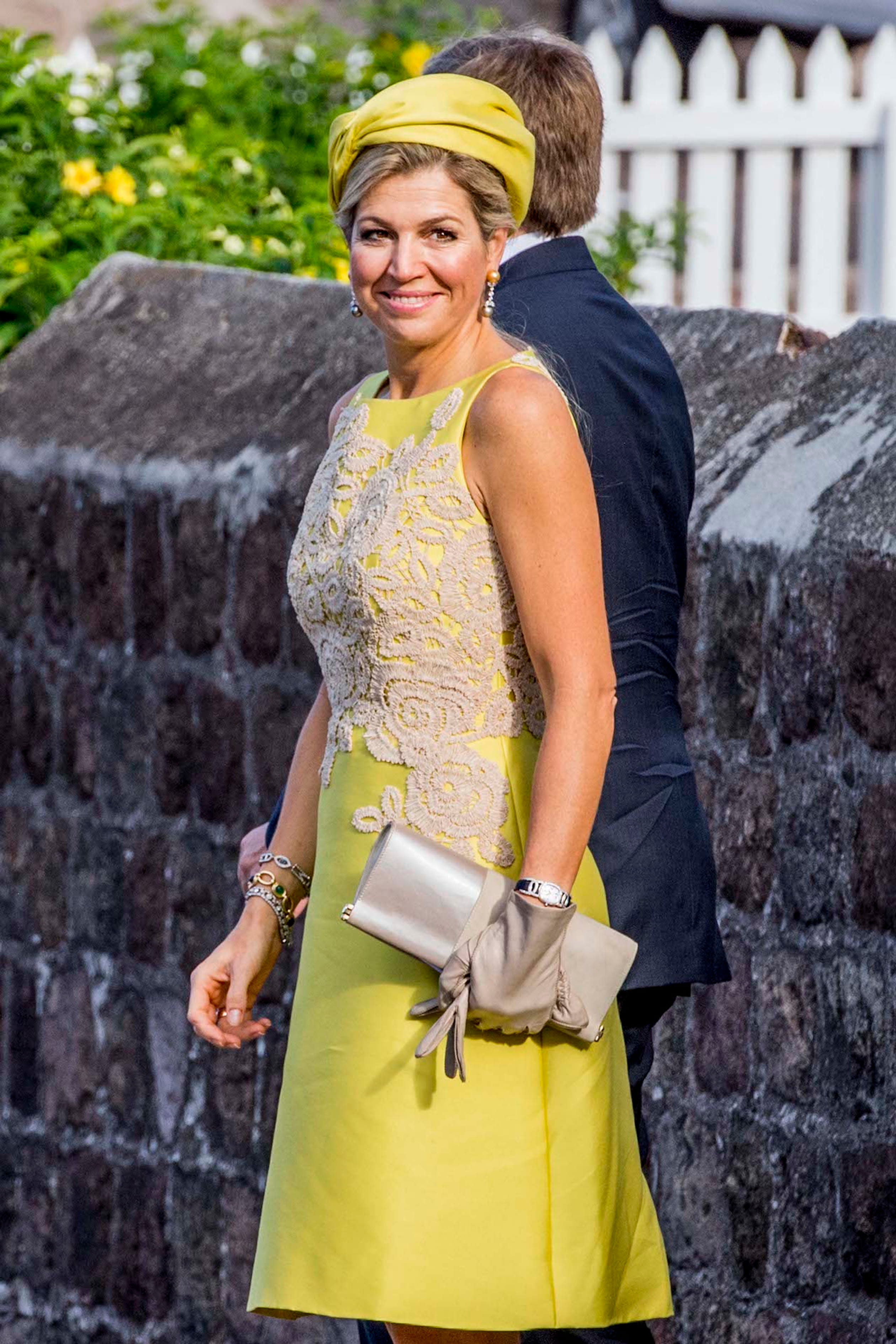Koningin Maxima straalt op Saba in een geel jurkje dat op het lijfje is bezet met poederkleurig