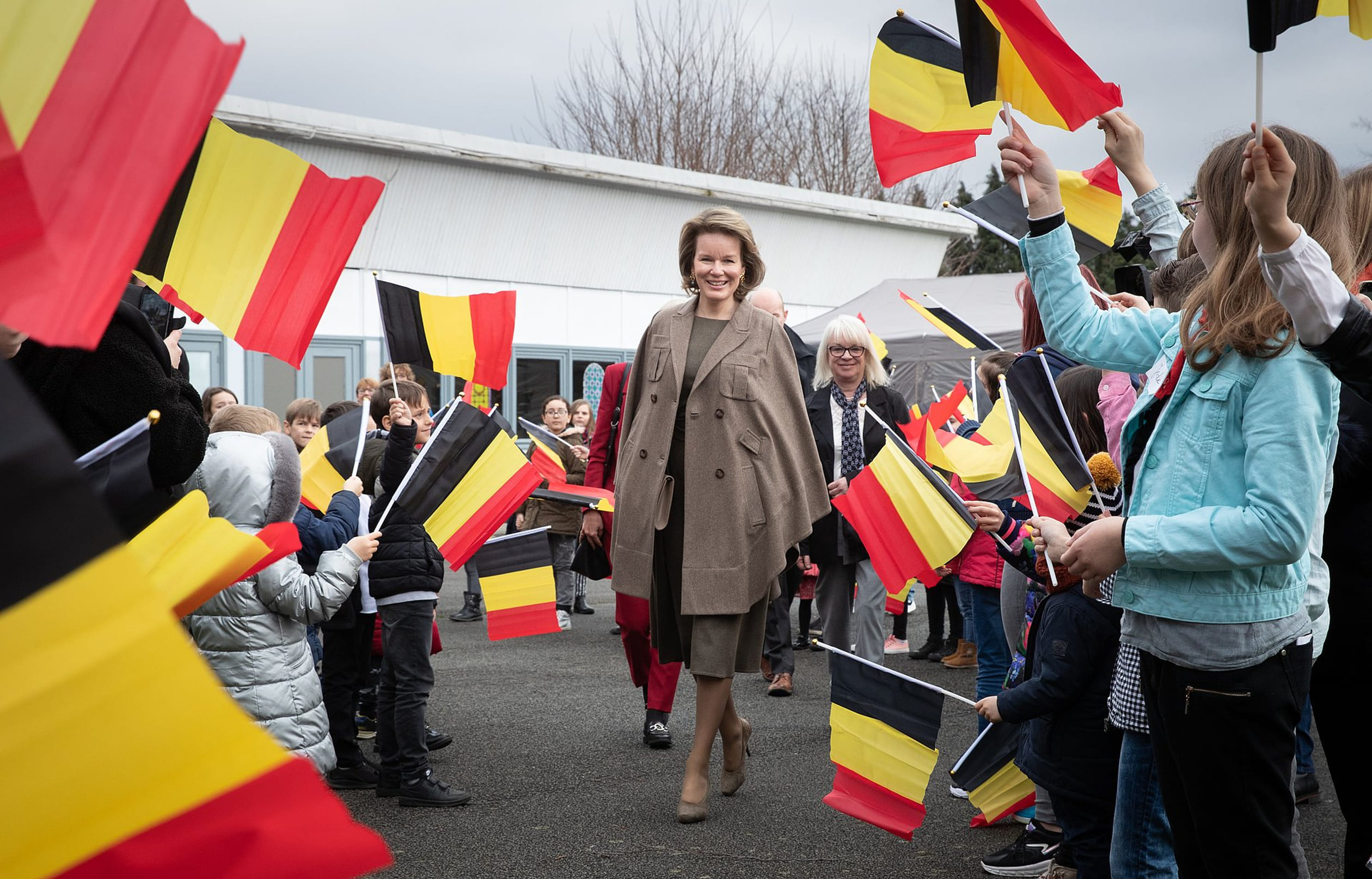 Studenten zwaaien met vlaggen als koningin Mathilde na haar bezoek aan het 'Fly to the Moon' project