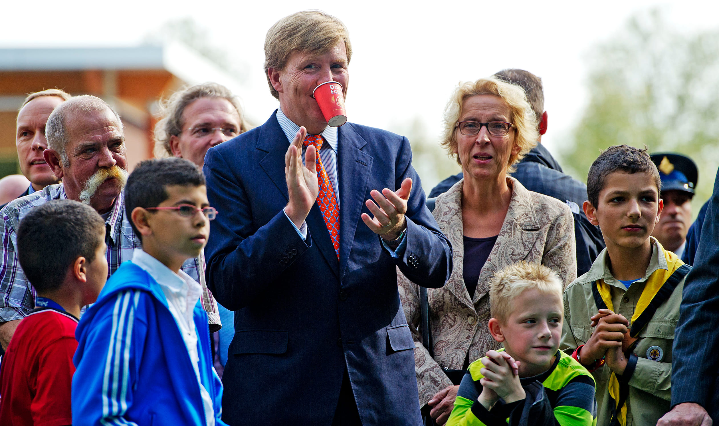 Een kop koffie drinken en aanmoedigen gaan niet echt samen. Willem-Alexander moedigt voetballende