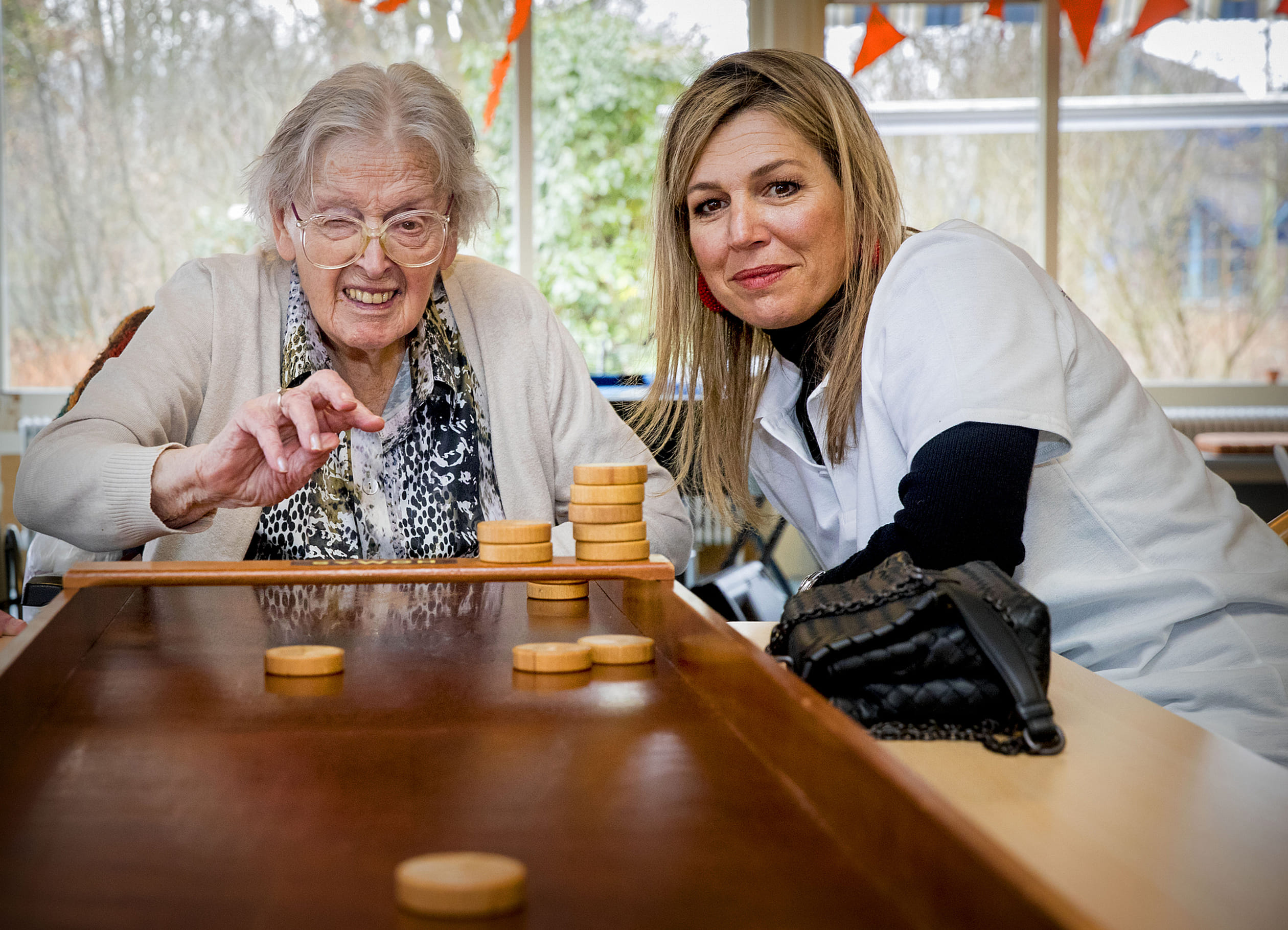 Máxima achter de sjoelbak tijdens de nationale vrijwilligersactie NLdoet, 2018.