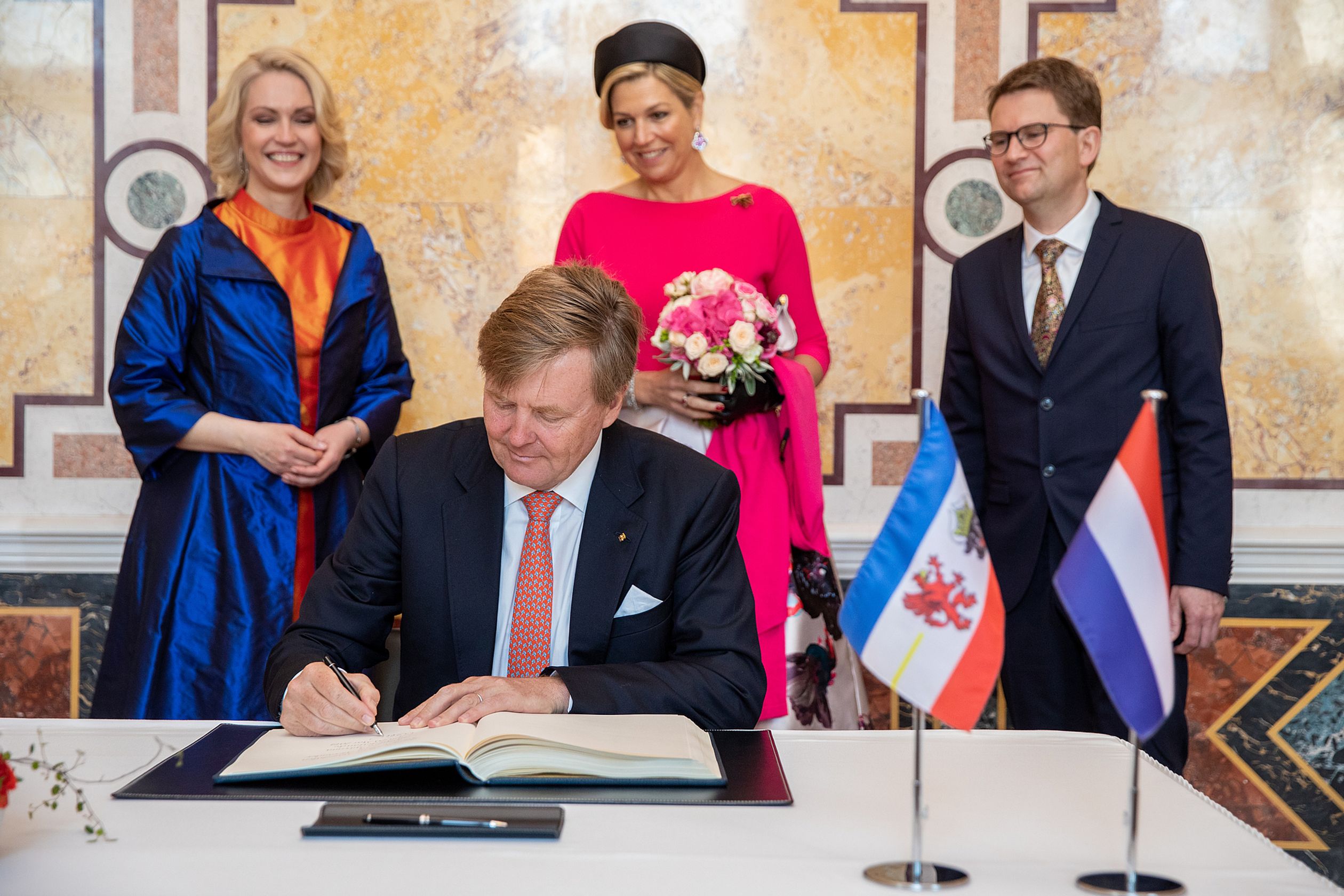 Koning Willem-Alexander tekent het gastenboek van de Duitse deelstaat, gevolgd door koningin Máxima.