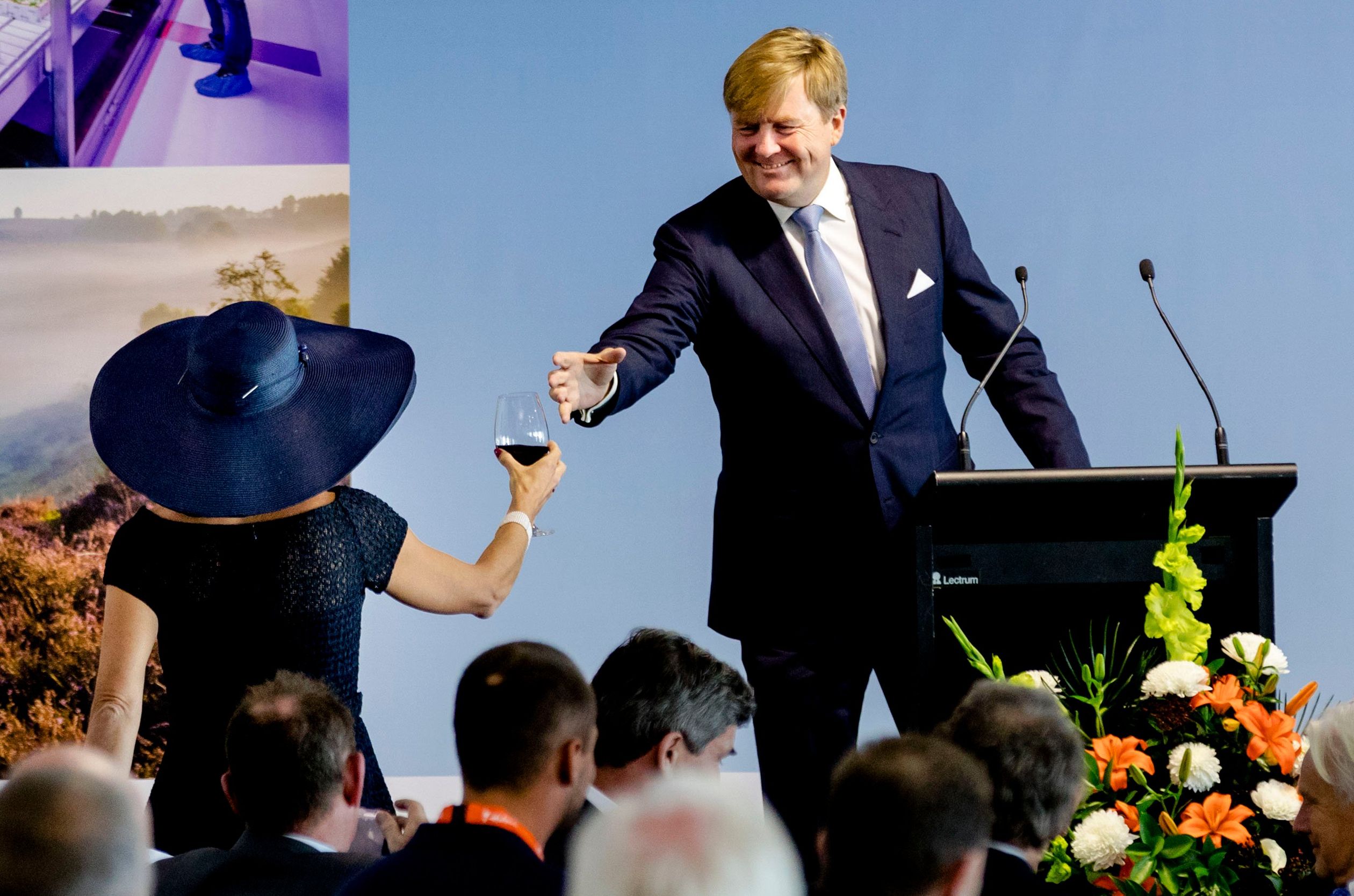 Koningin Máxima geeft een glas rode wijn aan koning Willem-Alexander tijdens zijn speech in Nieuw-Zeeland.
