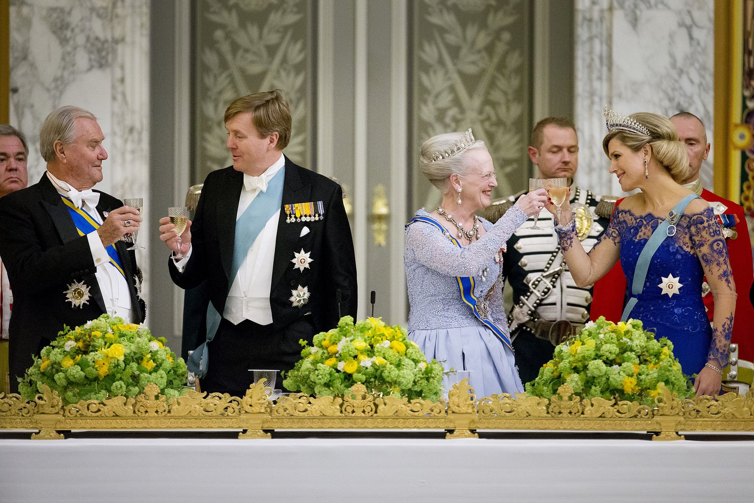 Een toost wordt uitgebracht tijdens het staatsbanket. V.l.n.r. zien we prins Henrik, koning Willem-Alexander, koningin Margrethe en koningin Máxima. Tijdens dit diner benadrukt Margrethe in een speech de hechte band tussen de koningshuizen.
