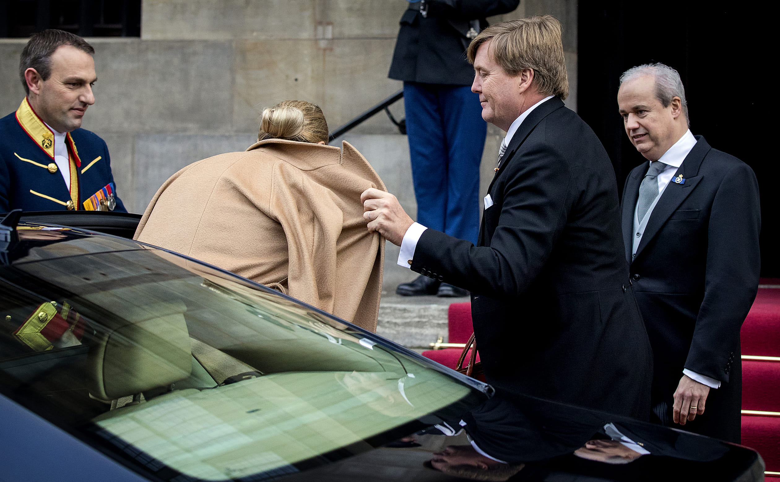 Willem-Alexander helpt Máxima met haar jas.