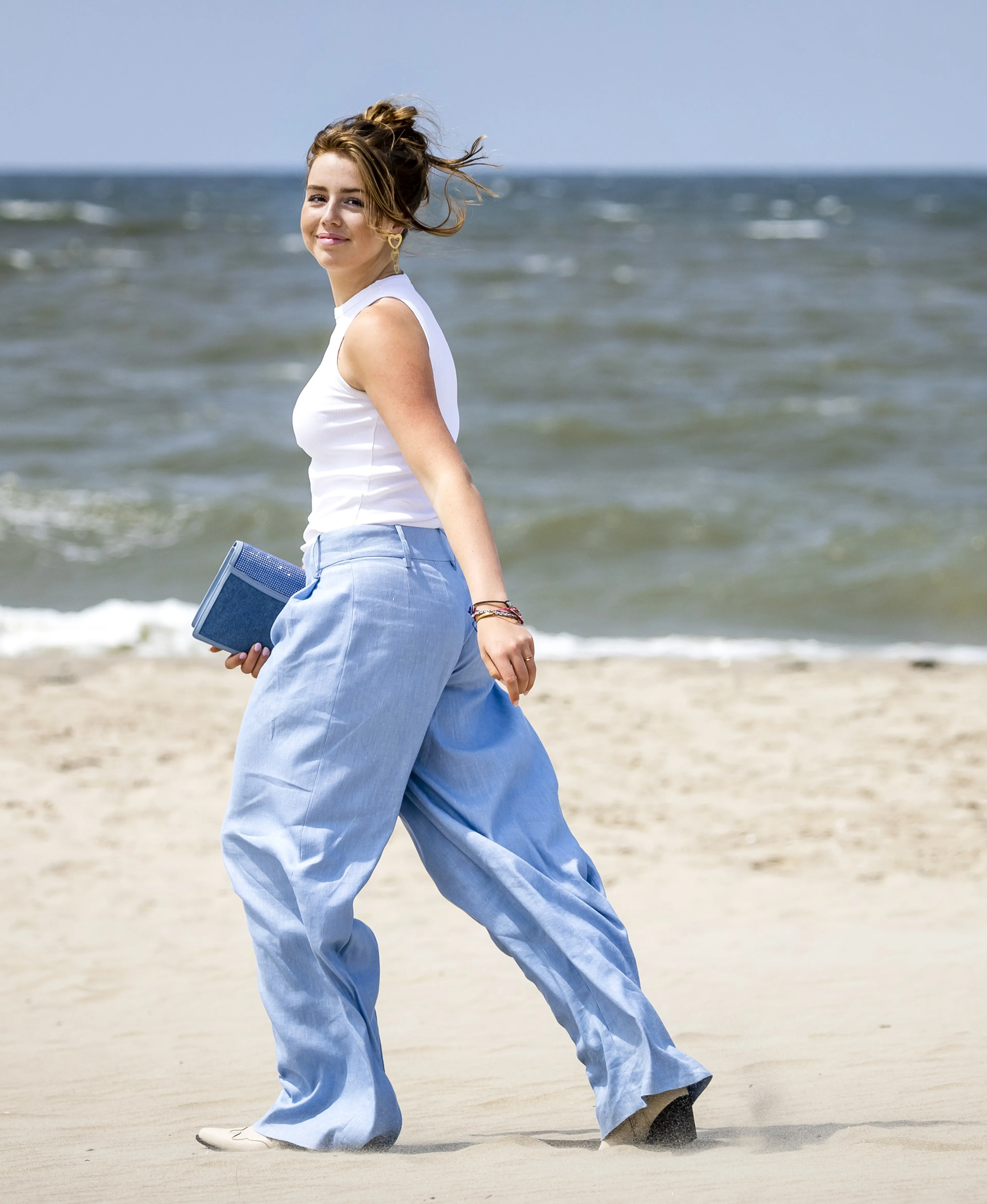 De prinses draagt een witte top en een blauwe broek.