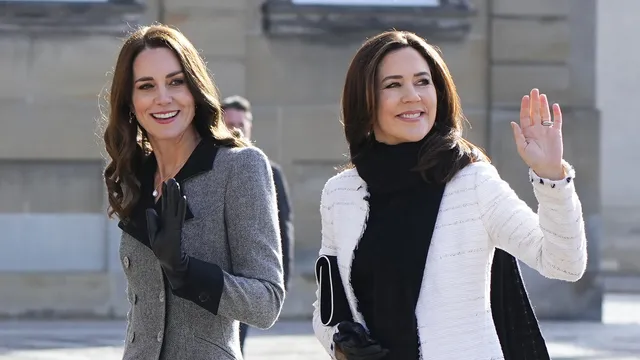 Catherine, de prinses van Wales en koningin Mary dragen hier allebei handschoenen. Koningin Mary heeft één handschoen uitgedaan om daarmee naar het publiek te zwaaien.