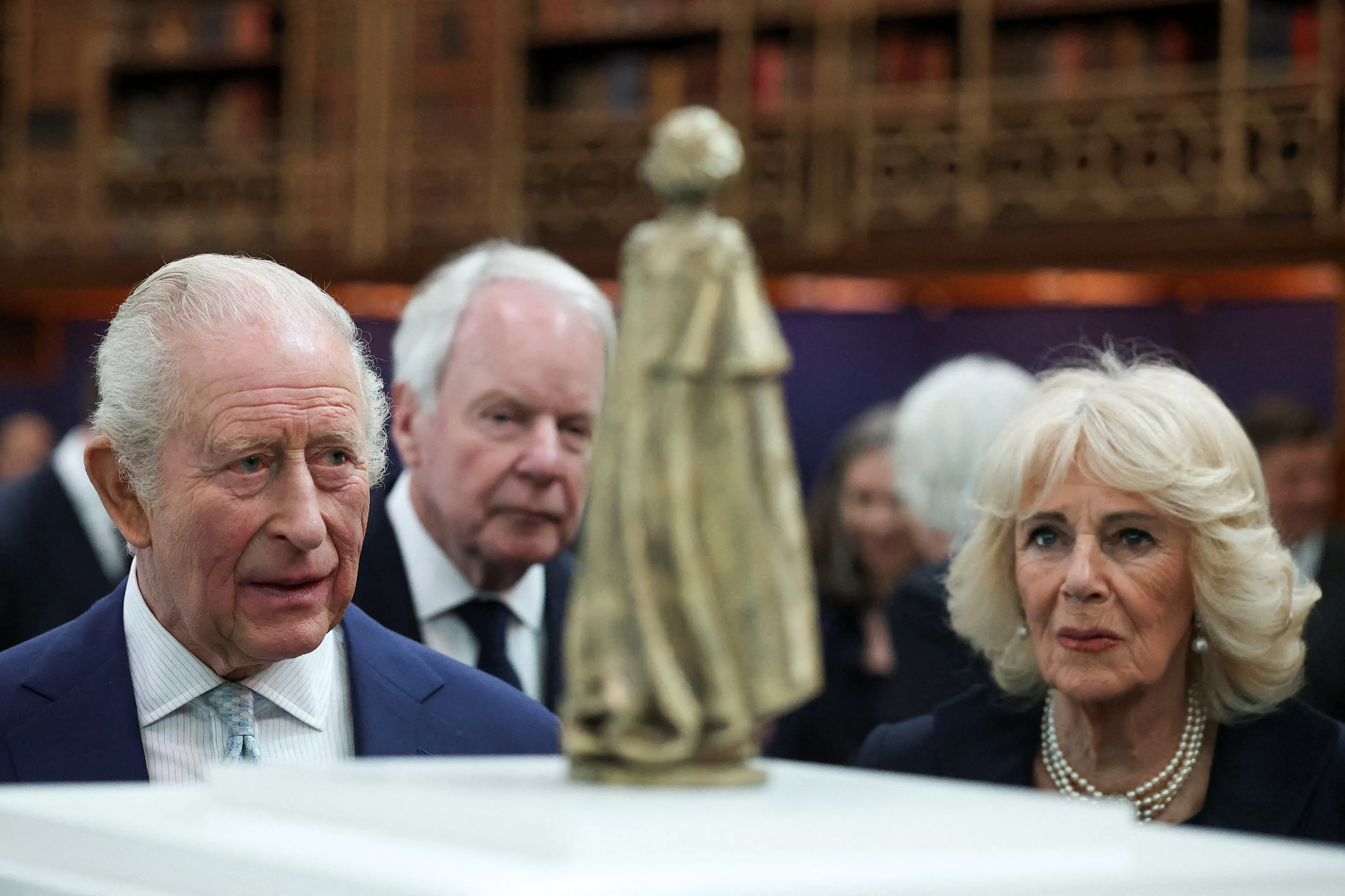 Het koningspaar kijkt naar een miniatuurversie van het standbeeld van koningin Elizabeth.